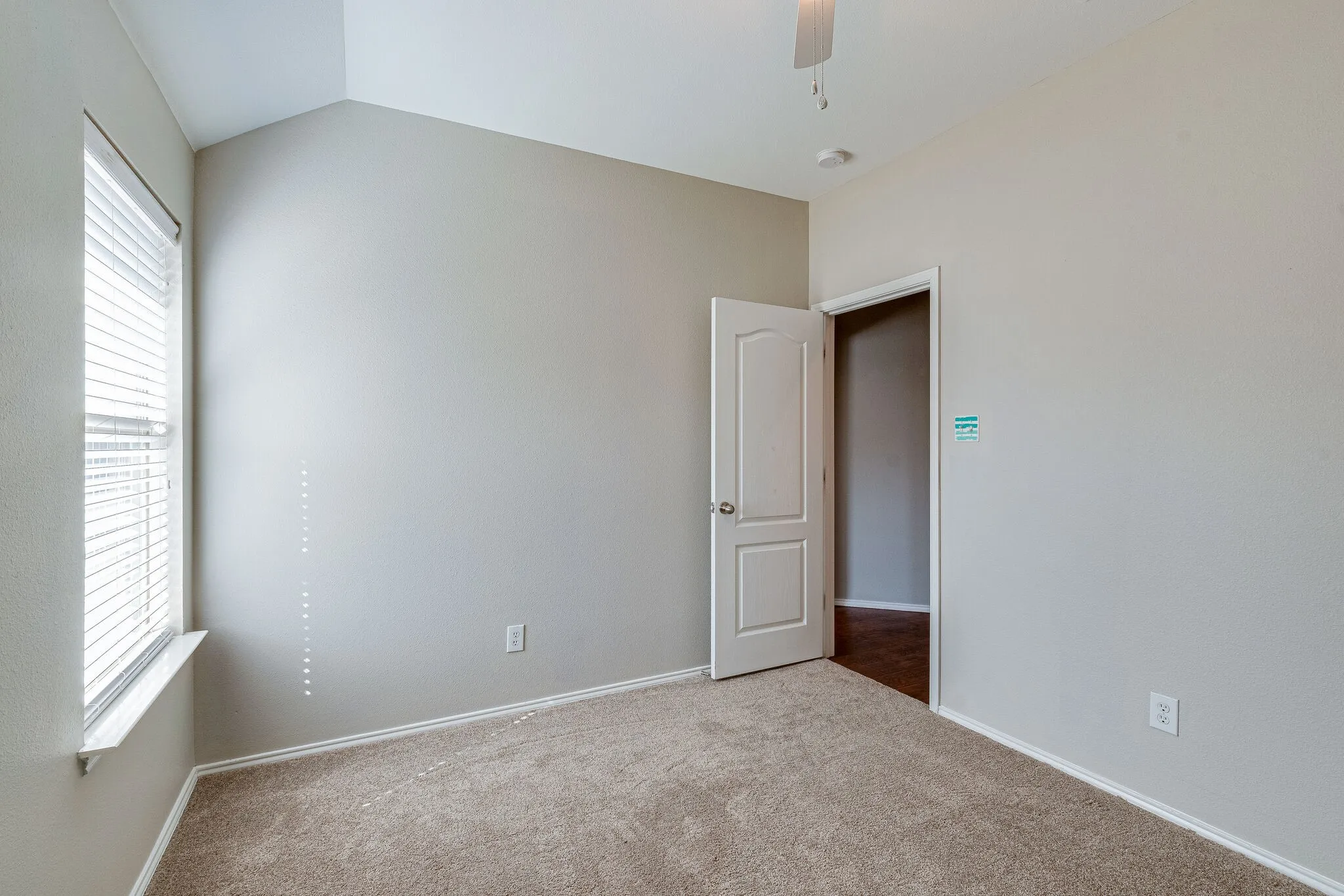 Vaulted ceiling with a ceiling fan, window with horizontal blinds, neutral wall paint, and carpet flooring