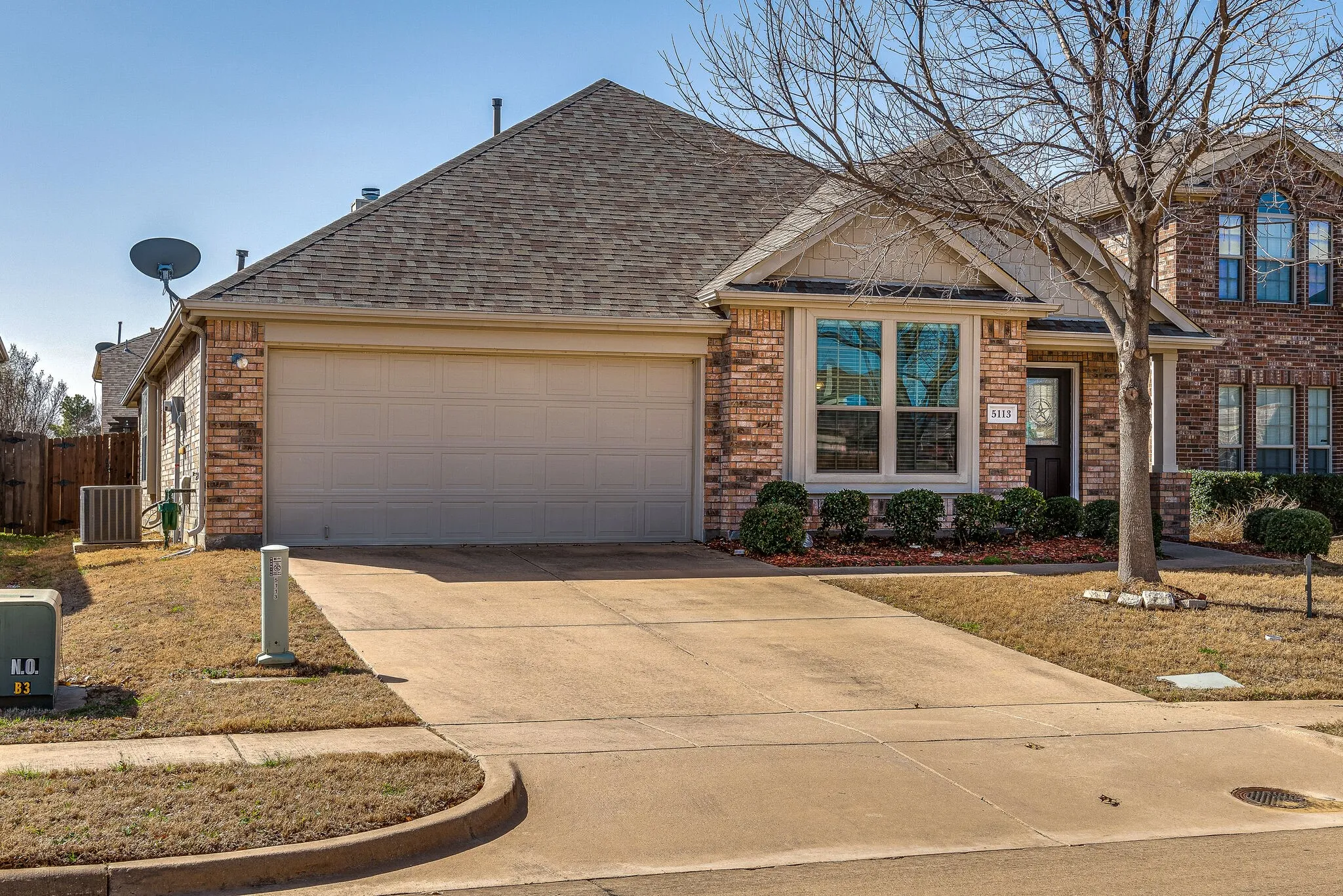 Brick exterior featuring a gabled roofline, attached garage, and a concrete driveway