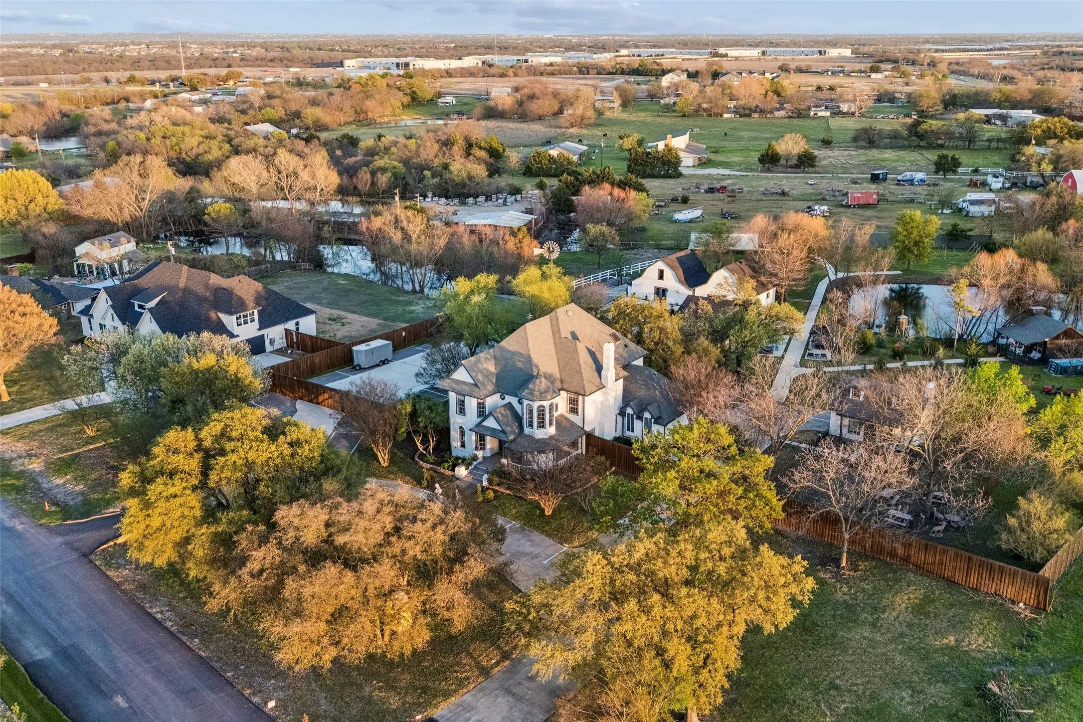 Spacious property featuring a large residence with a multi-gabled roof, surrounded by mature trees