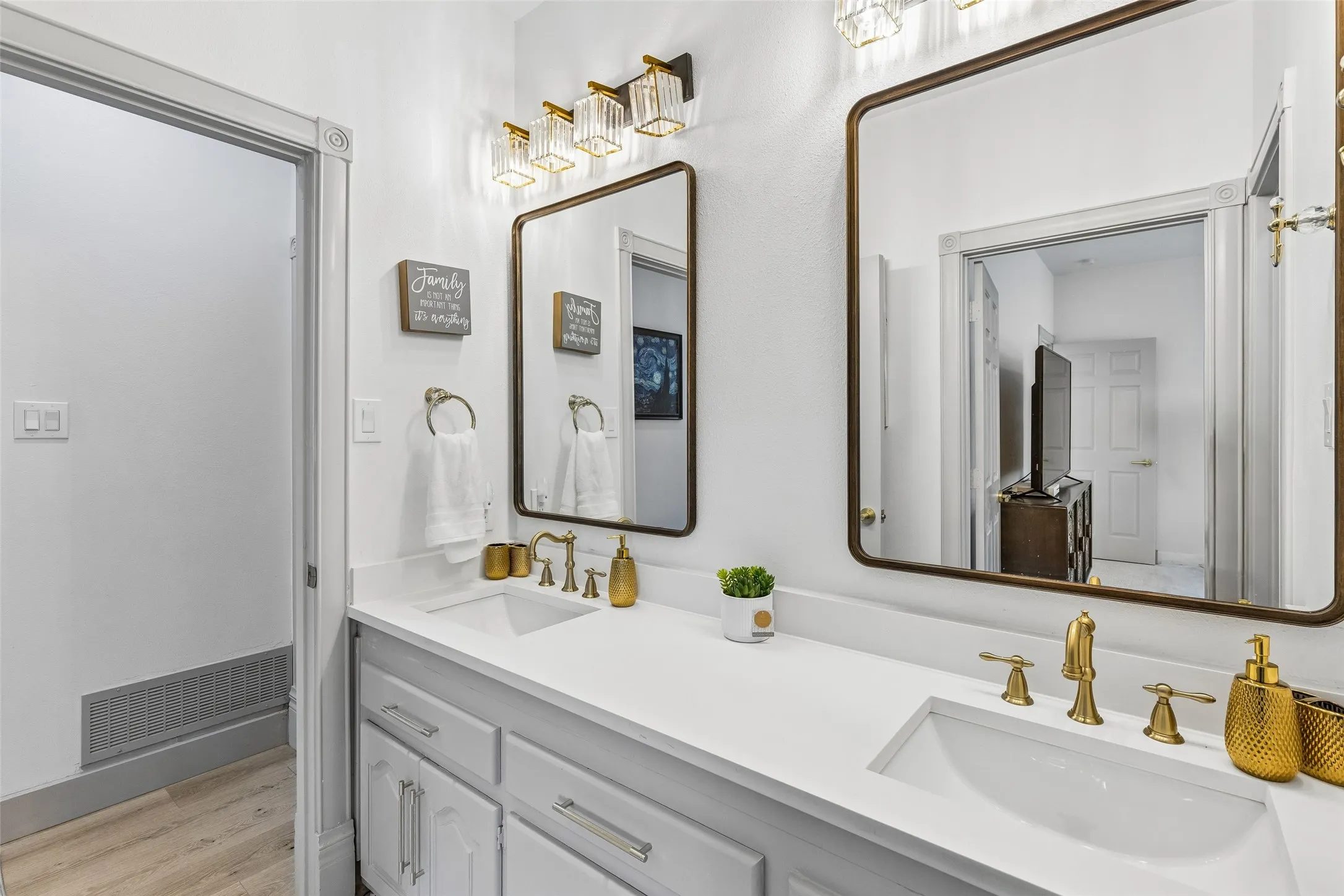 Dual vanity with integrated sinks and white countertops, complemented by gold-finish fixtures and framed mirrors