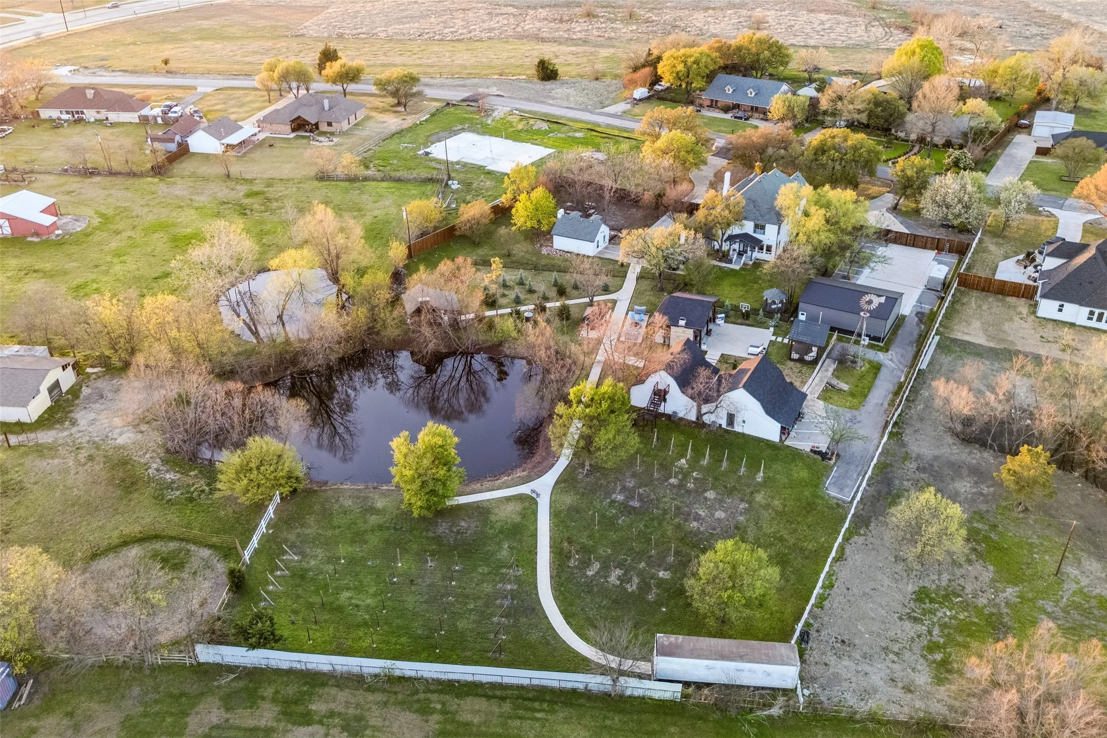 Expansive property featuring a private pond surrounded by mature trees, multiple structures, and a dedicated driveway