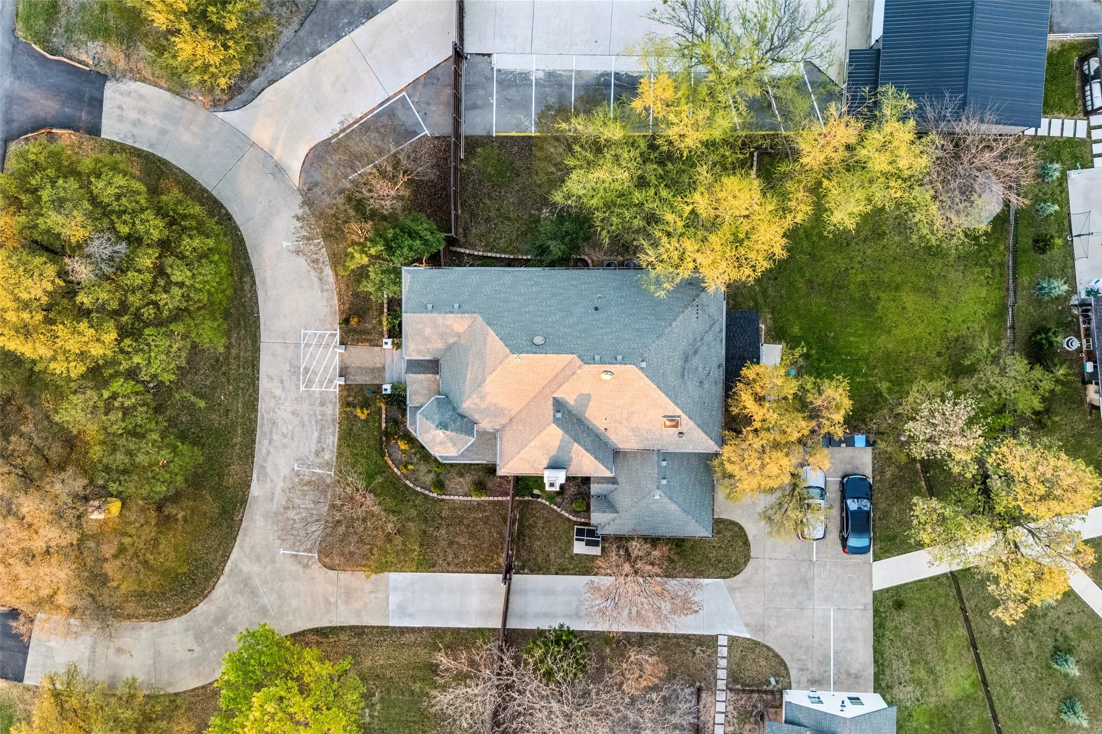 Expansive lot with mature trees, a multi-car driveway, and a well-defined paved access road