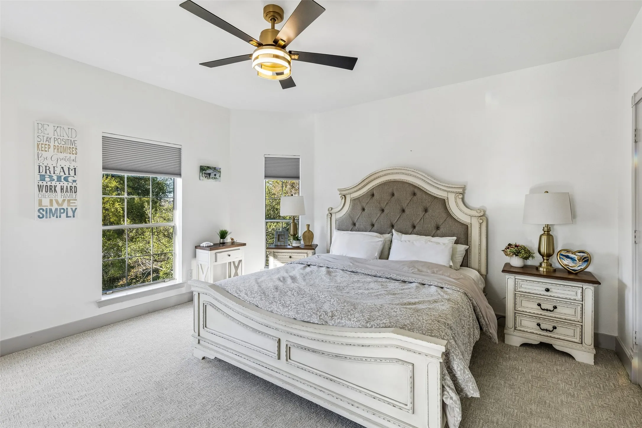 Plush carpet flooring, multiple windows with blinds, and a ceiling fan with integrated lighting