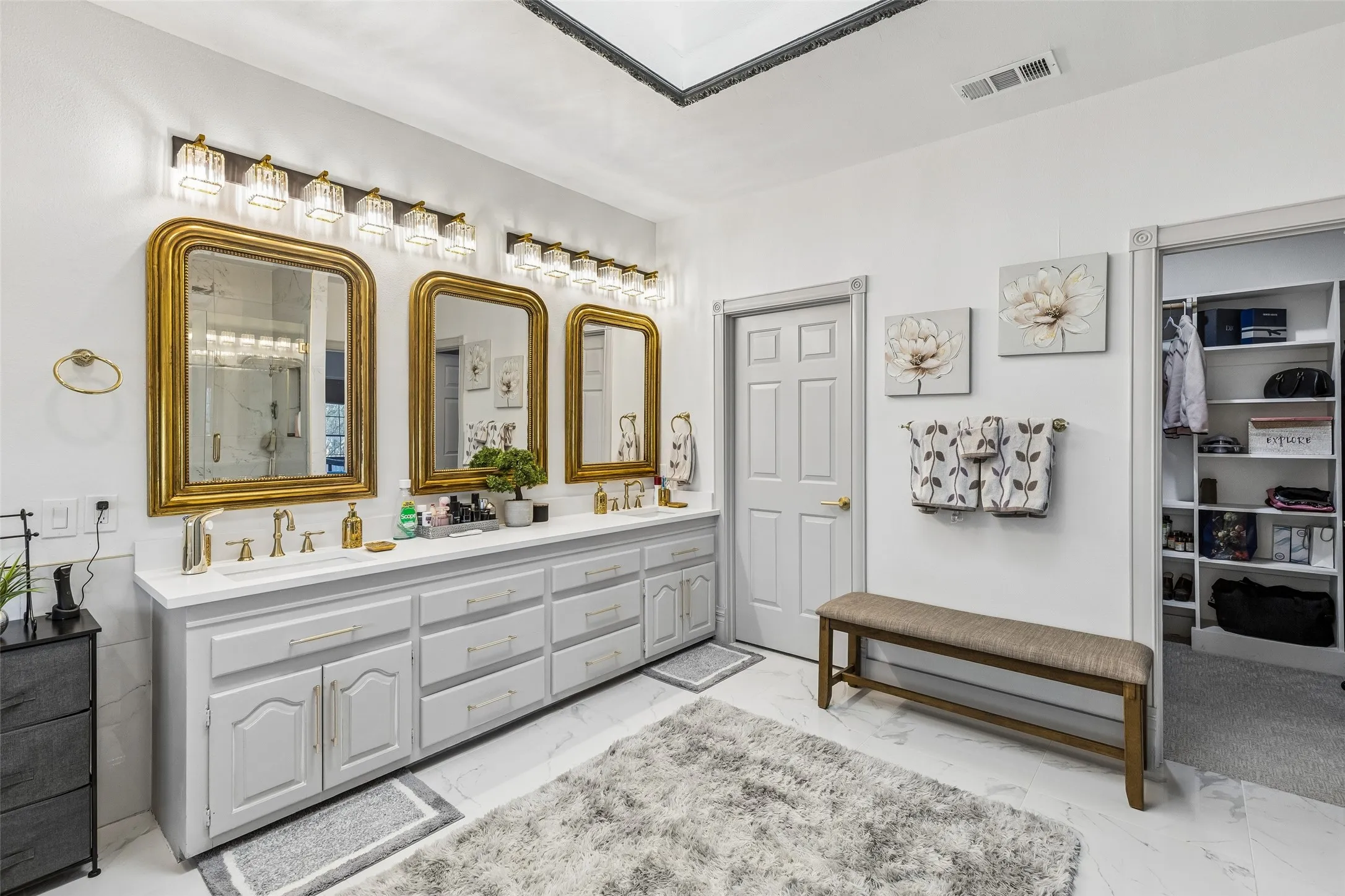 Dual vanity with light gray cabinetry, white countertops, and gold-framed mirrors