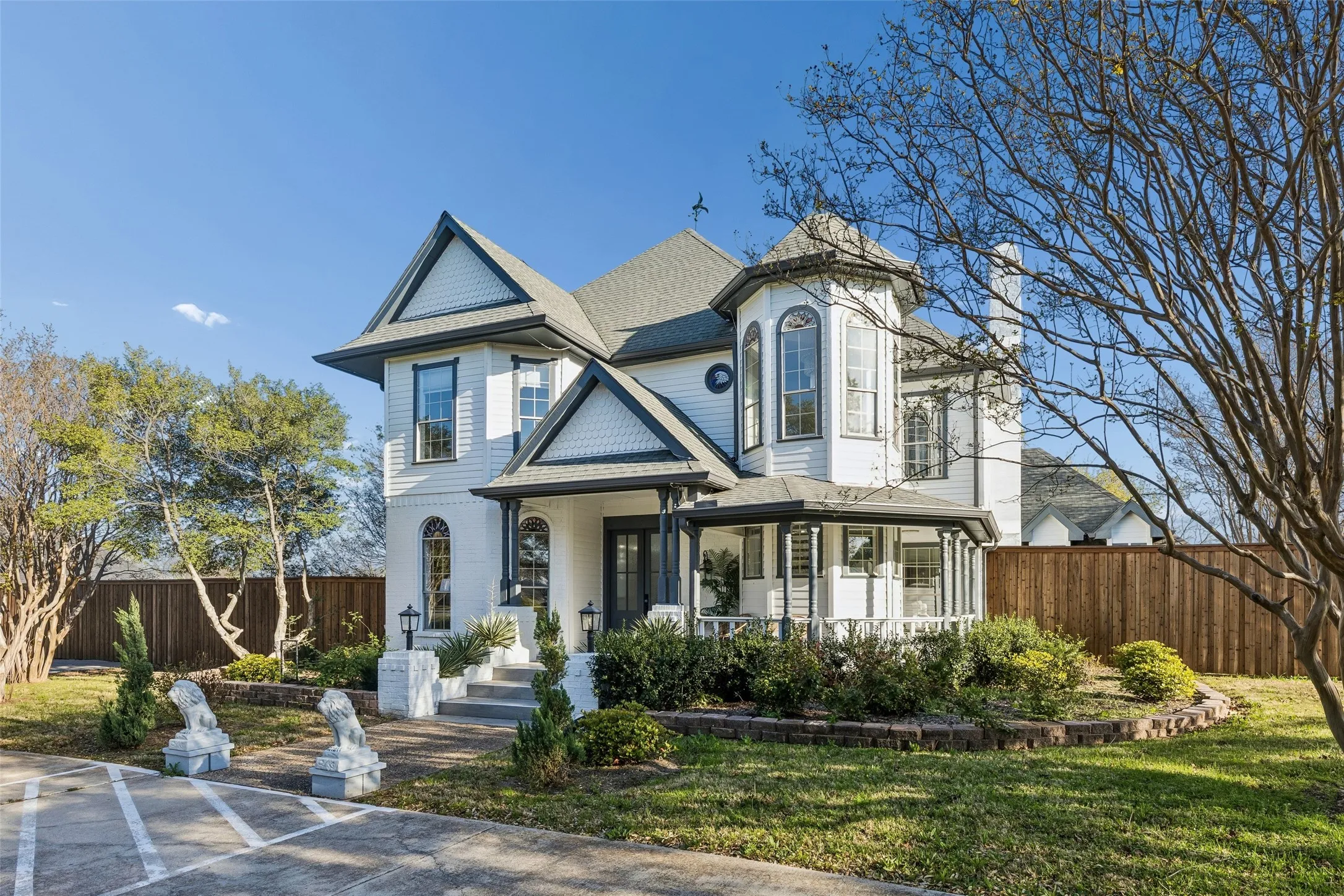 Victorian-style exterior with white siding and dark trim, featuring a prominent turret and a covered front porch