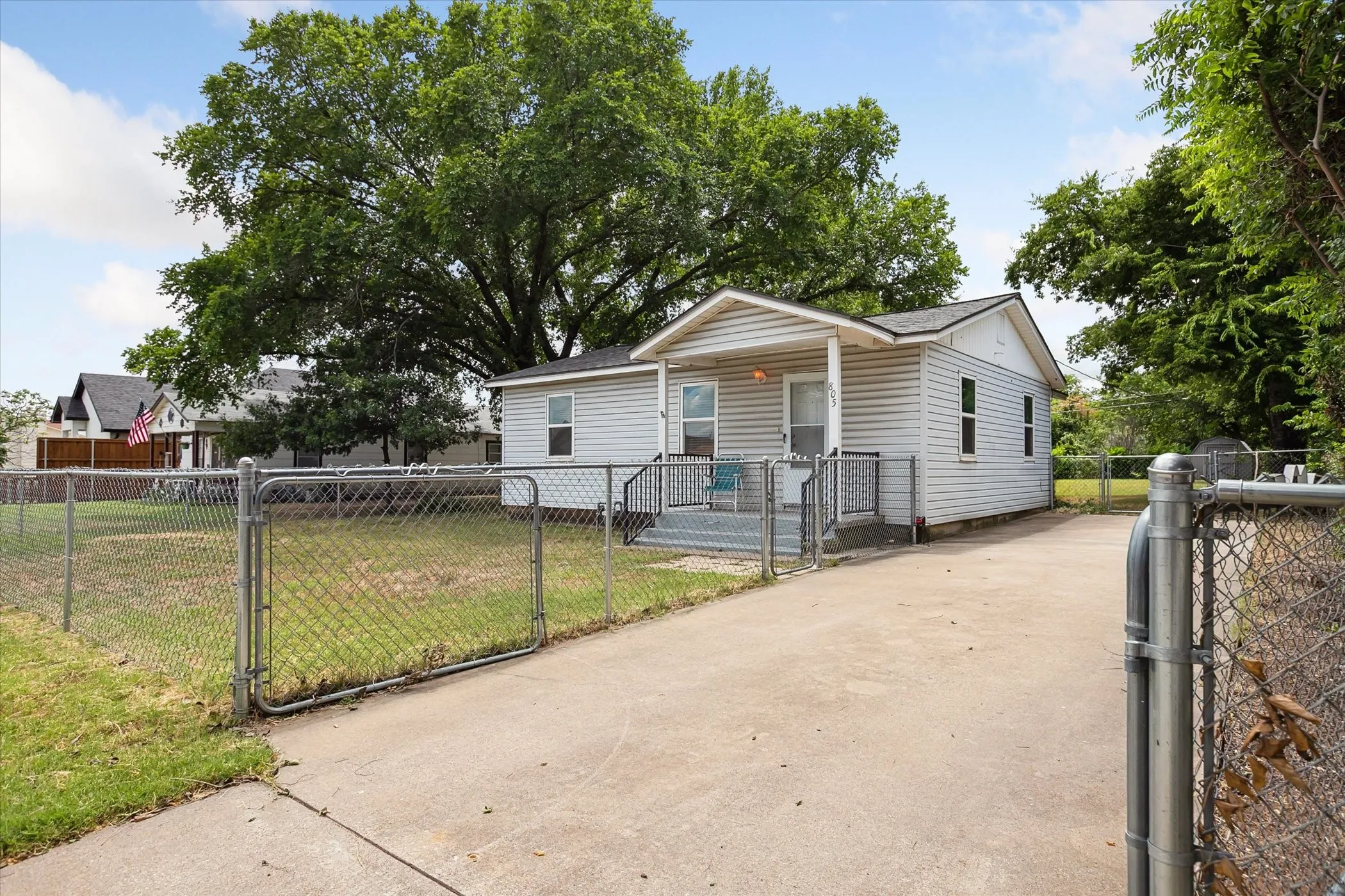 Siding exterior with a covered porch, chain-link fencing, and a concrete driveway