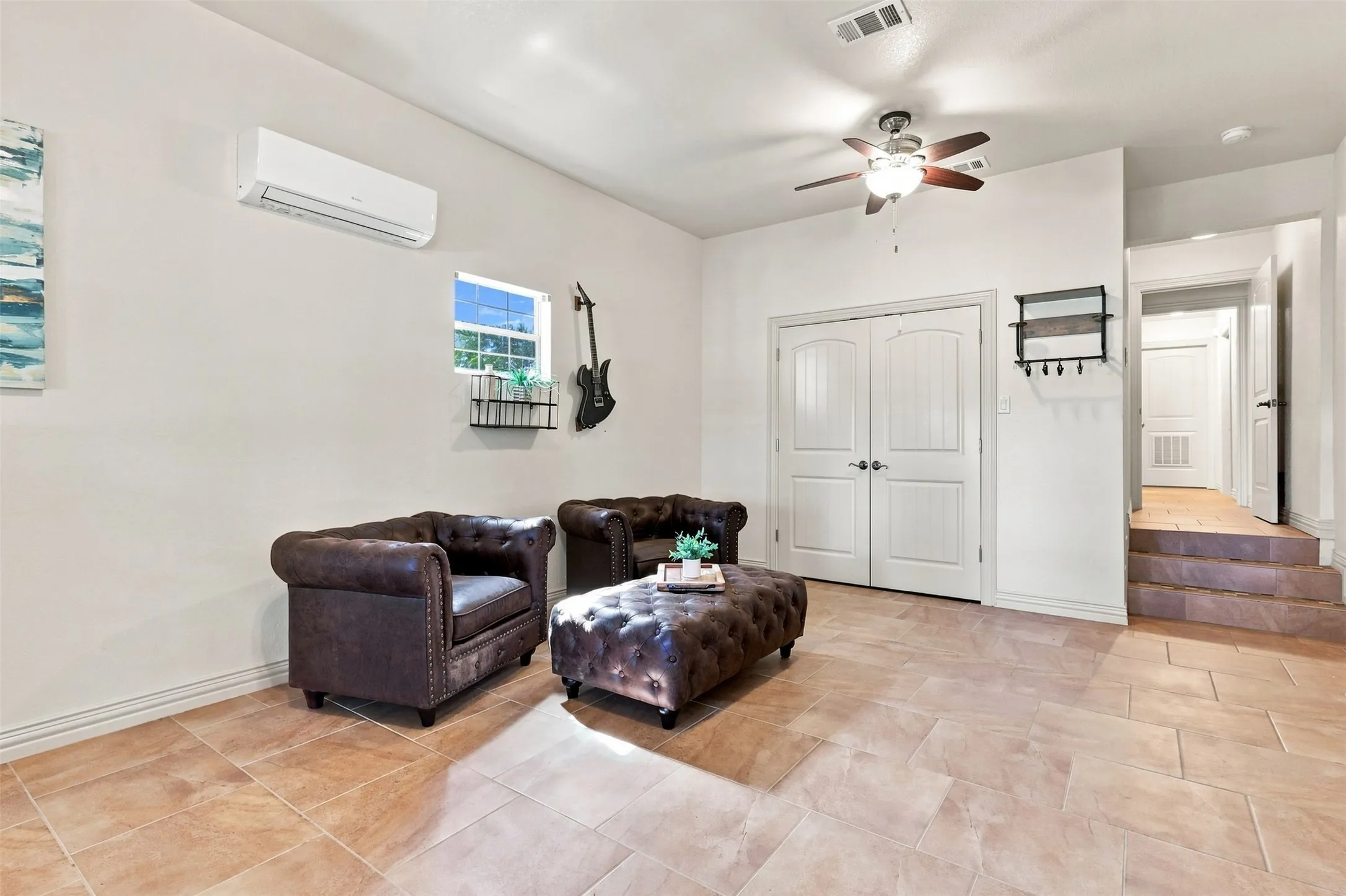 Tiled flooring, white walls, double panel doors, ceiling fan, and mini-split air conditioning unit