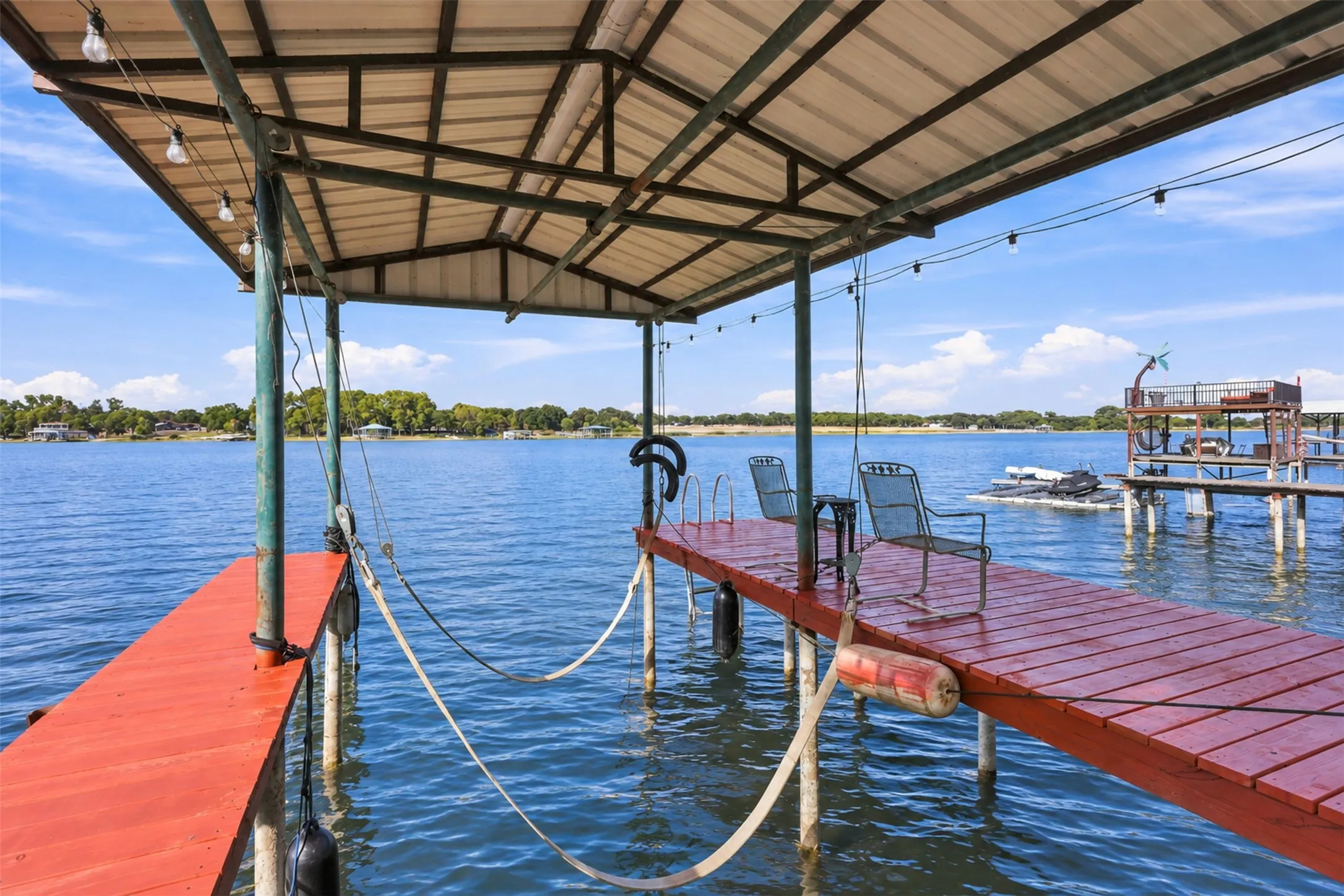 Covered boat dock with an extended wooden deck, metal canopy, and integrated string lighting