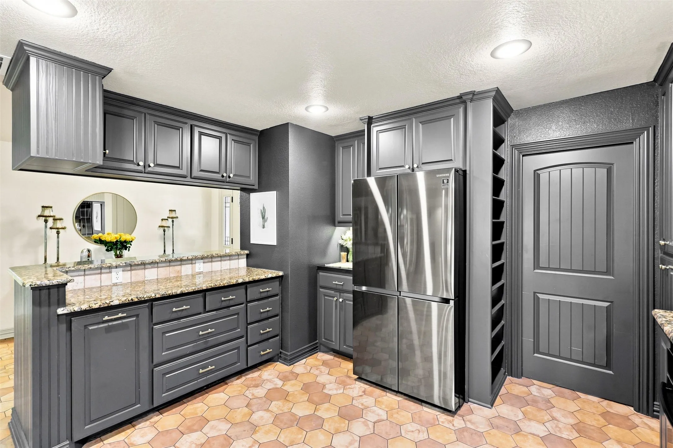 Hexagonal tile flooring, dark gray cabinetry, stainless steel refrigerator, built-in wine storage, and a paneled door