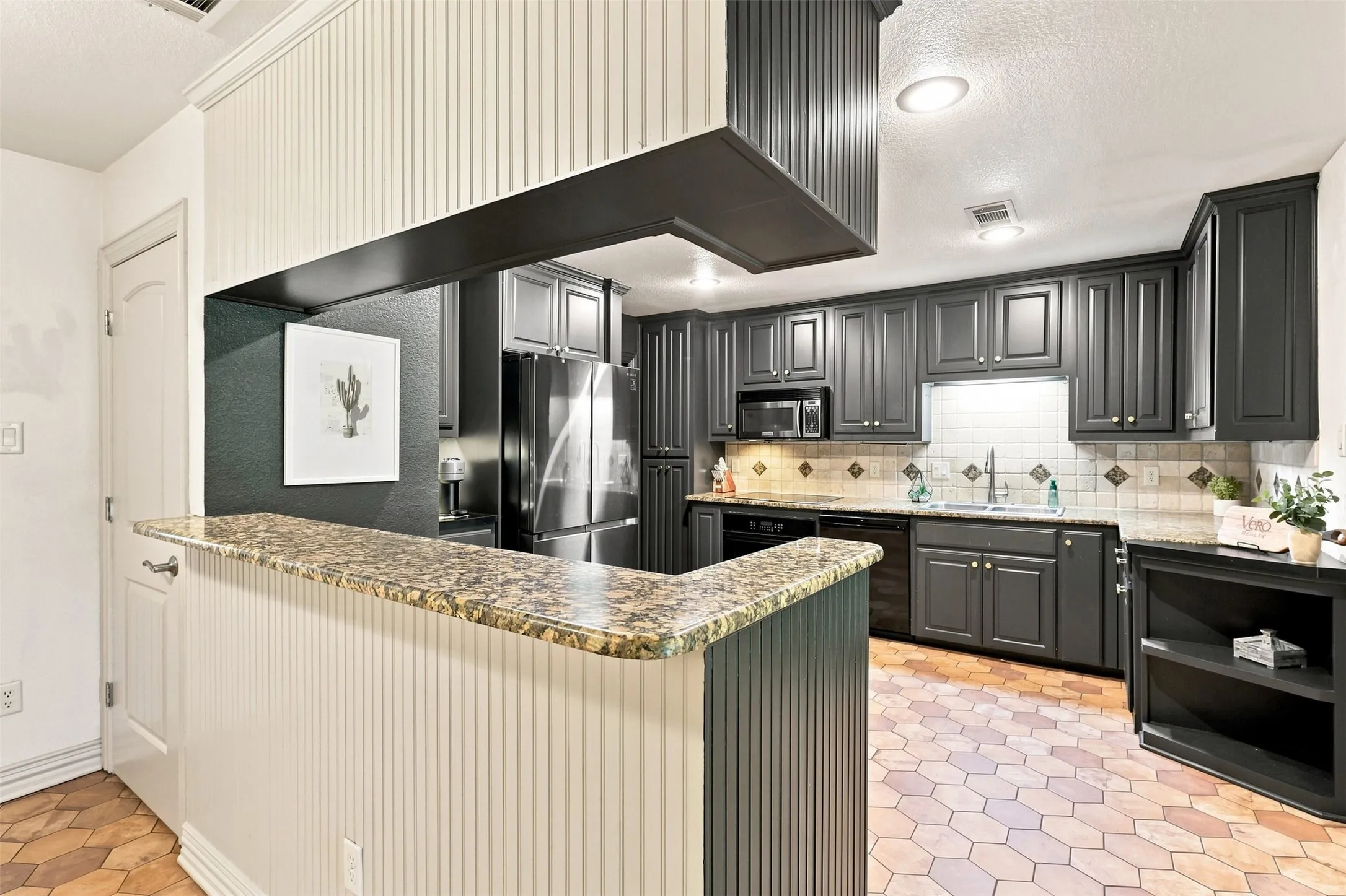 Kitchen featuring beautiful cabinetry, light-toned countertops, a stainless steel refrigerator, and a tiled backsplash