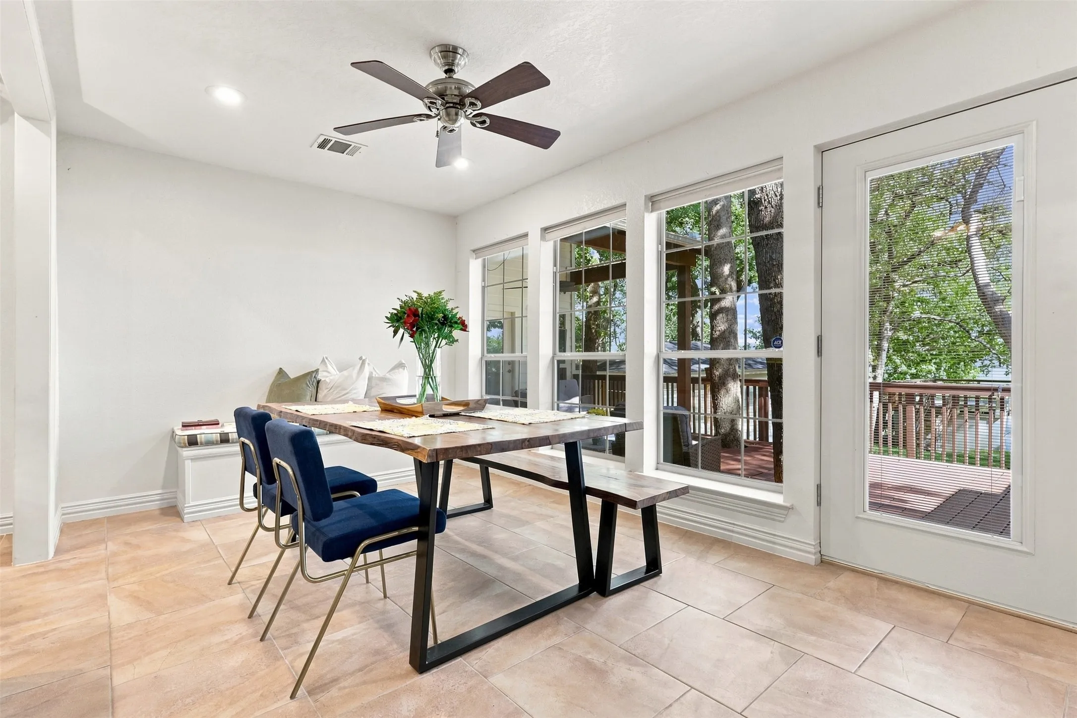 Recessed lighting, ceiling fan, built-in window seating, tile flooring, and glass-paneled door to deck