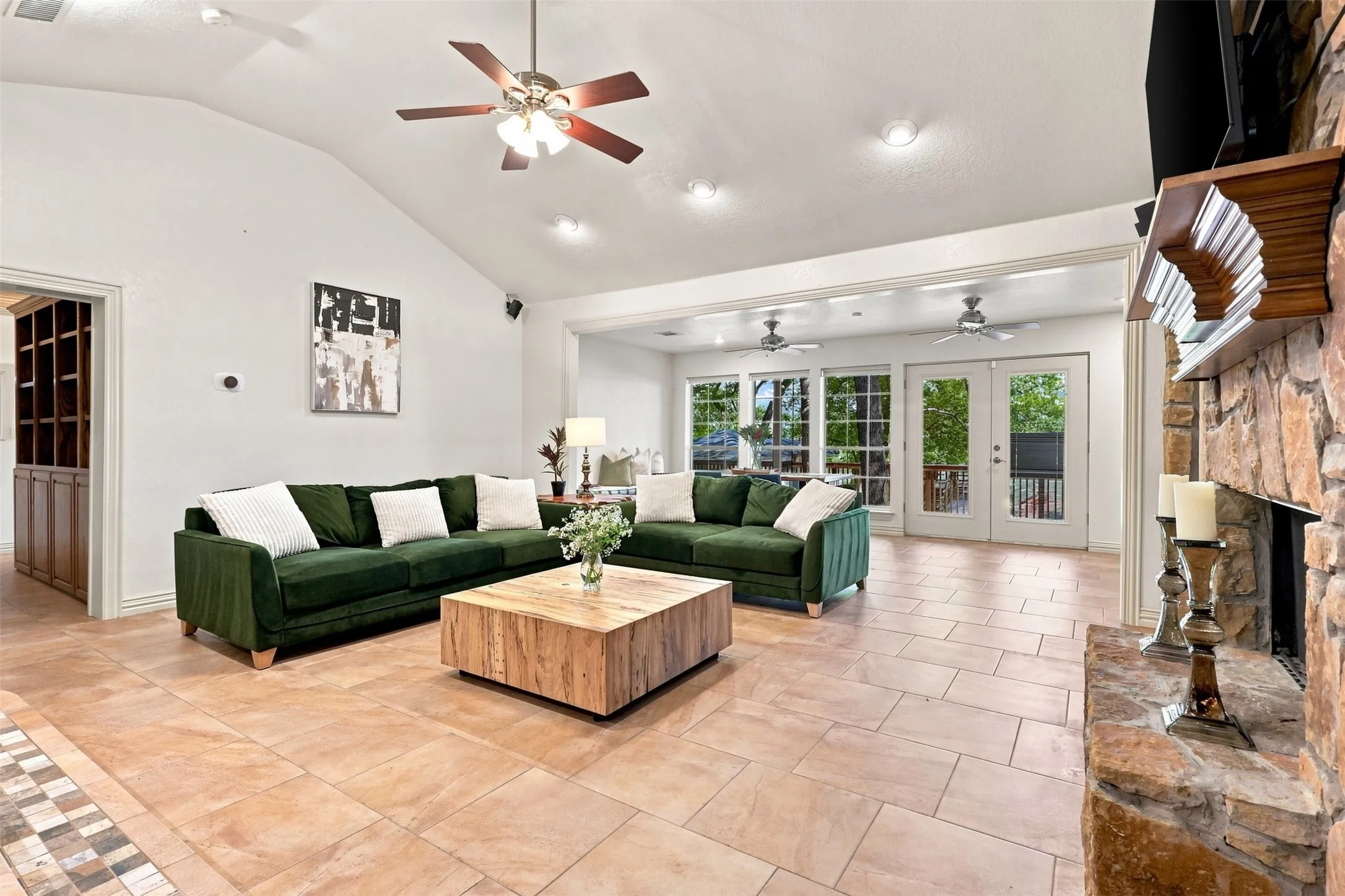 Vaulted ceiling with recessed lighting and ceiling fan, stone fireplace, and tile flooring