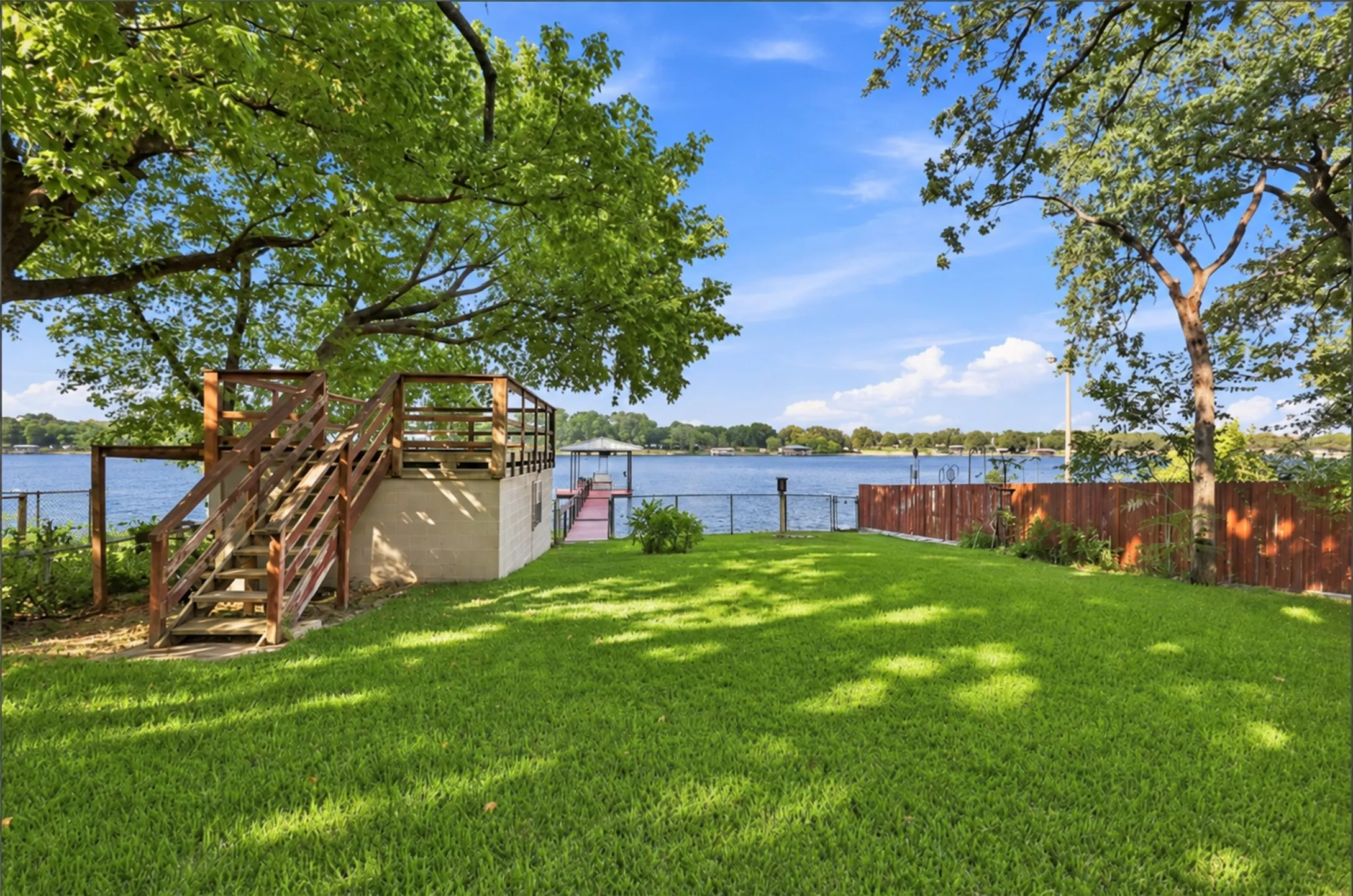 Expansive lawn with mature trees, a multi-level deck, direct water access, and a private boat dock
