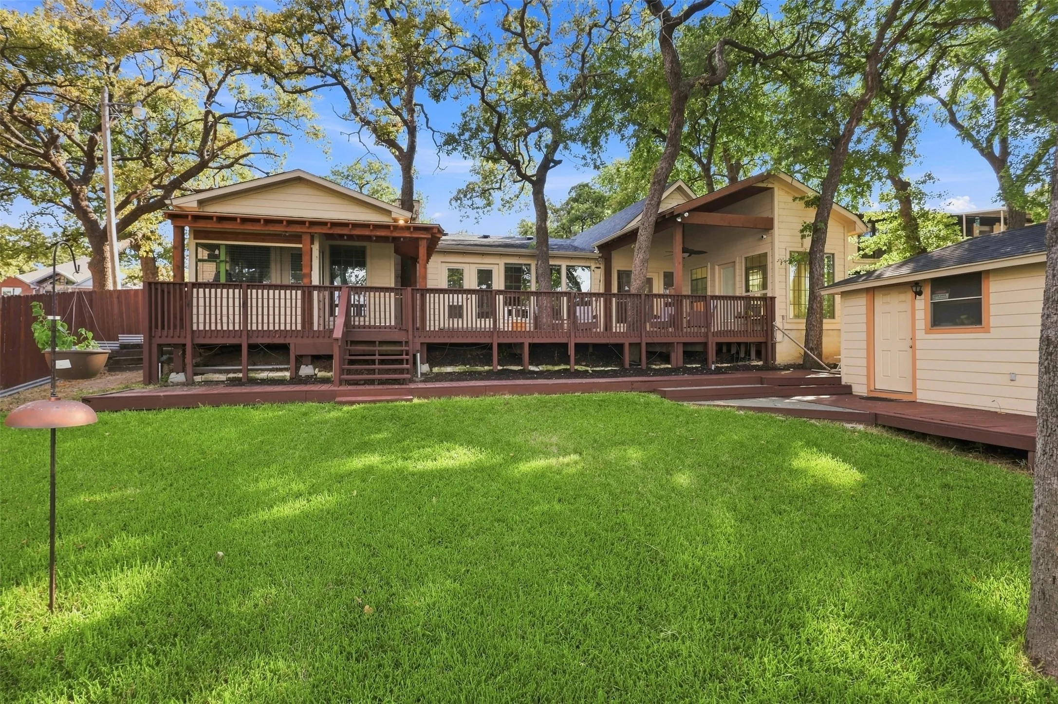 Expansive green lawn with a multi-level wood deck and a detached storage shed