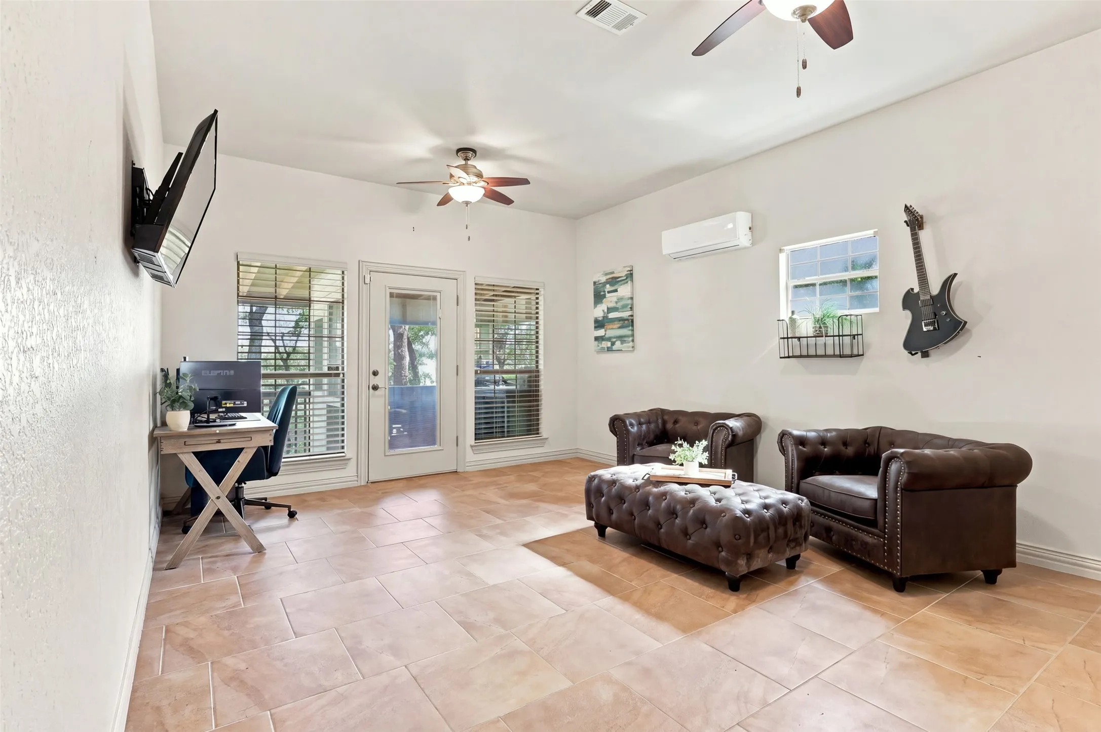 Tiled flooring, multiple ceiling fans, wall-mounted air conditioning unit, and exterior access via a glass-paneled door