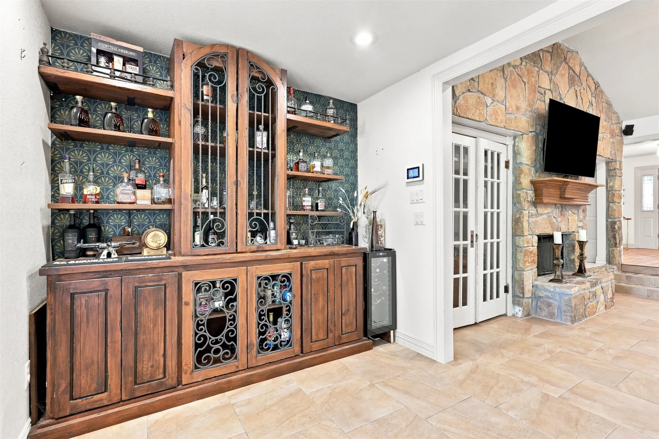 Built-in wooden cabinetry with ornate glass and metal details, open shelving, and a beverage cooler