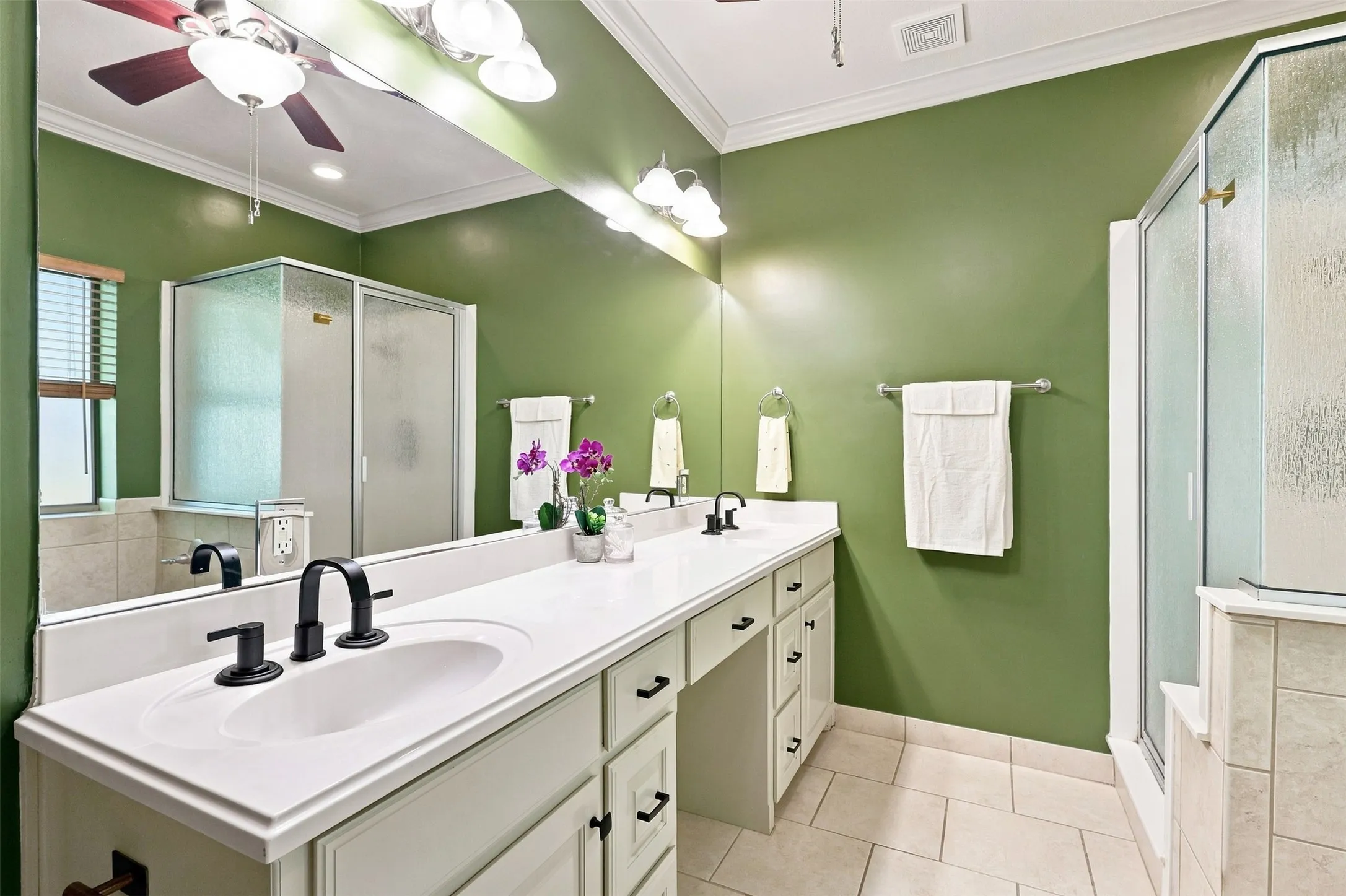 Dual vanity with white countertop and black fixtures, tiled flooring, built-in shower, and mirrored wall
