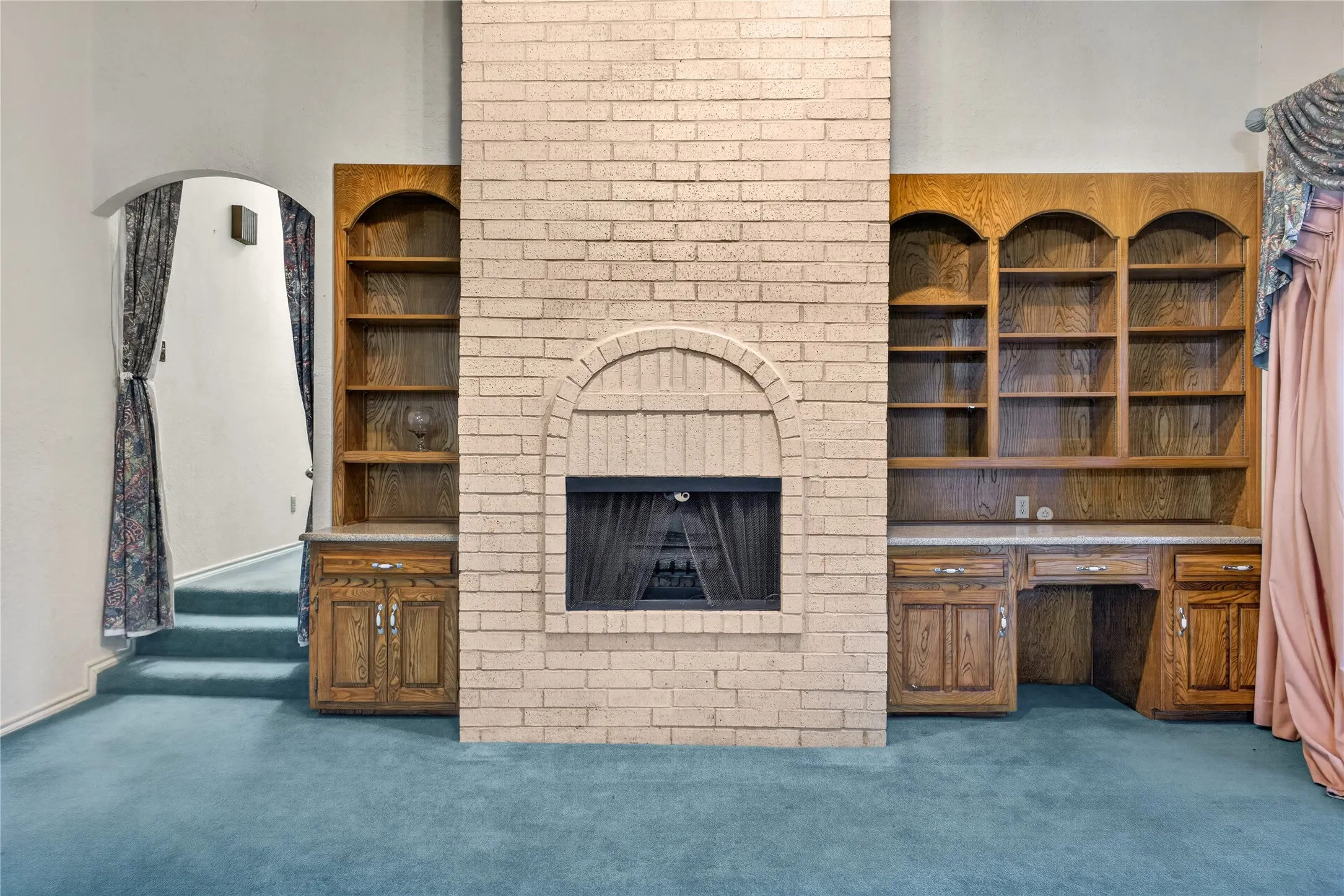Floor-to-ceiling brick fireplace with arched firebox and built-in shelving.
