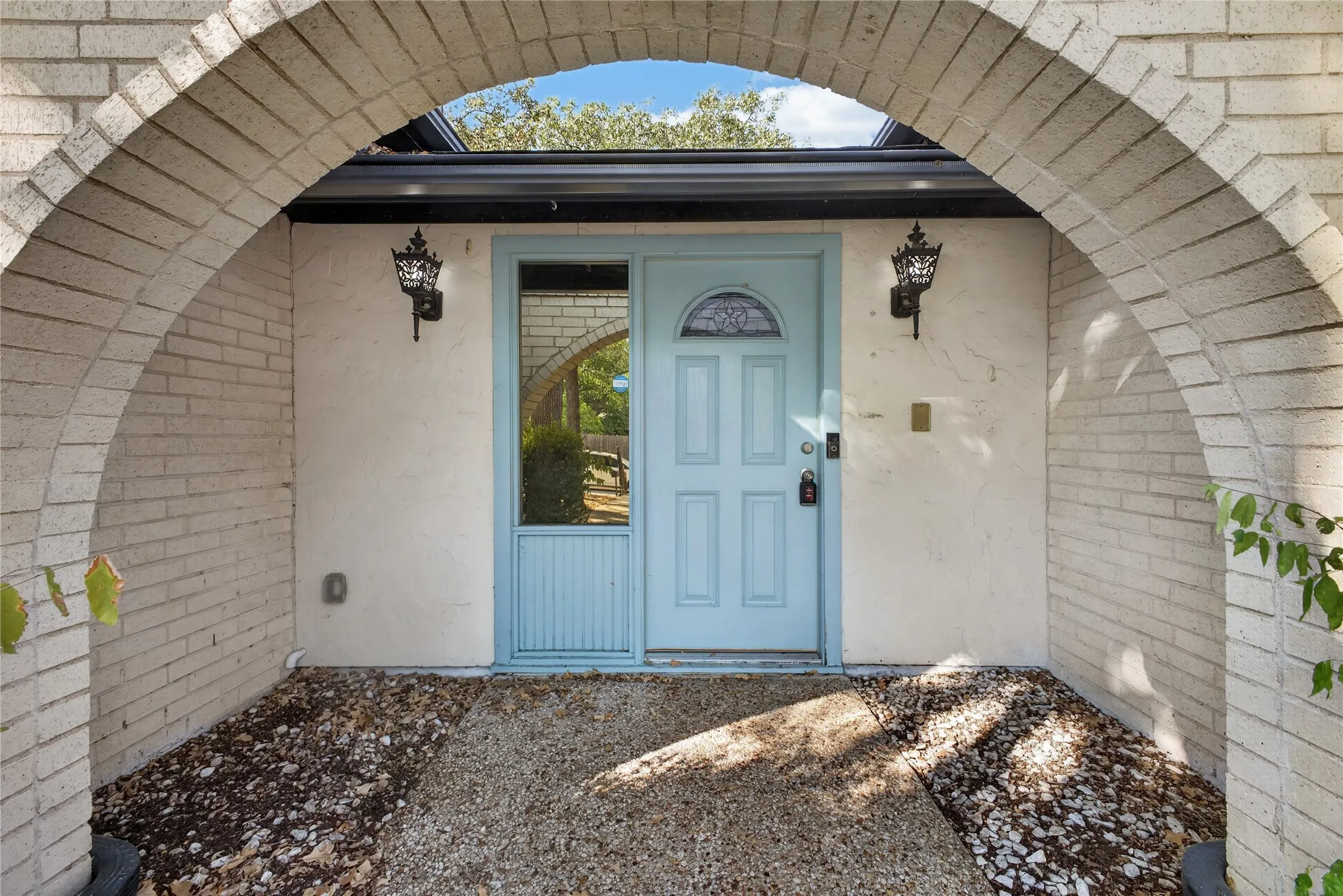 Arched brick entry introduces the home’s Spanish-inspired architectural character.