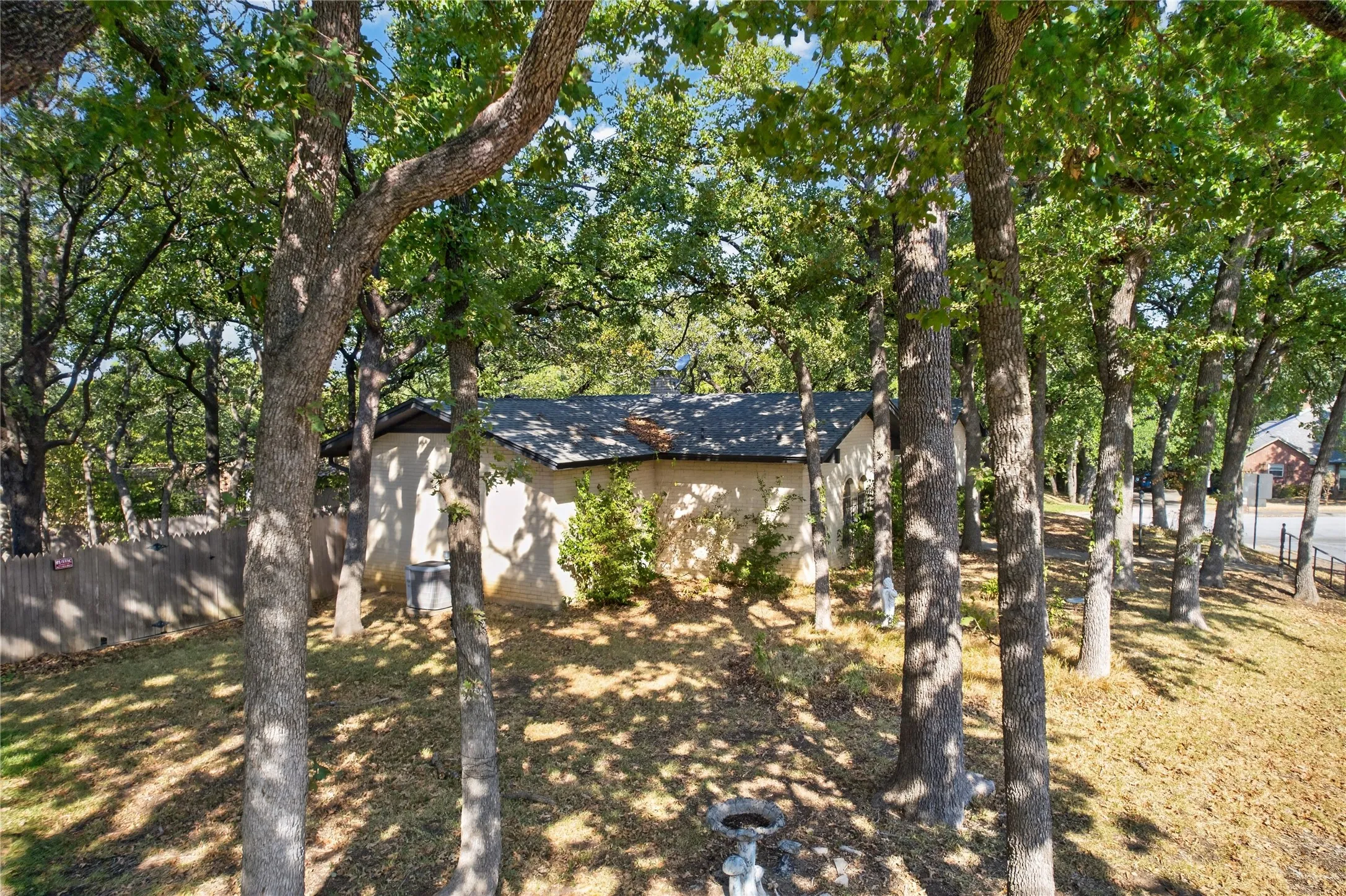 Mature trees create a shaded setting across the oversized corner lot.