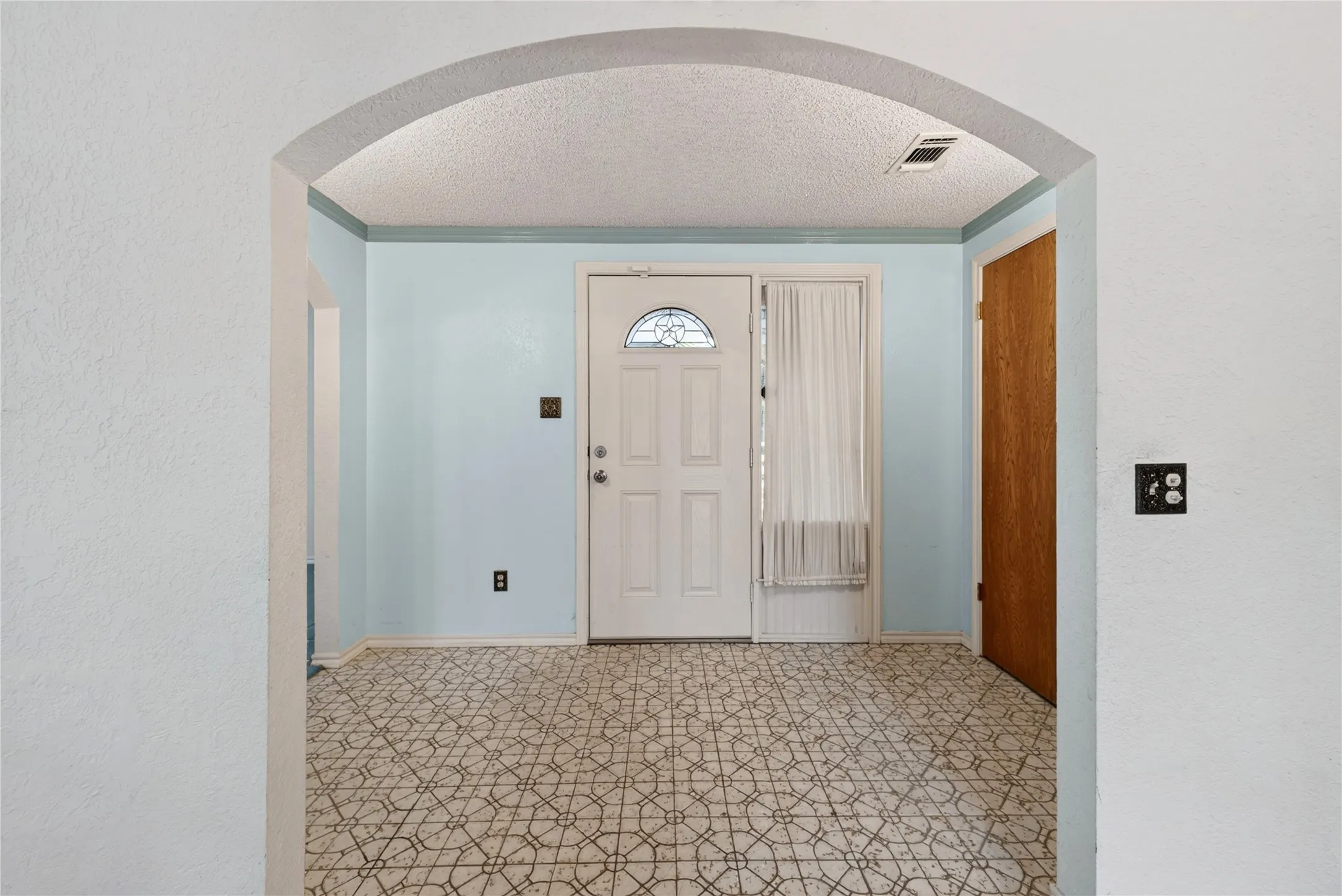 Arched entryway with original patterned flooring.