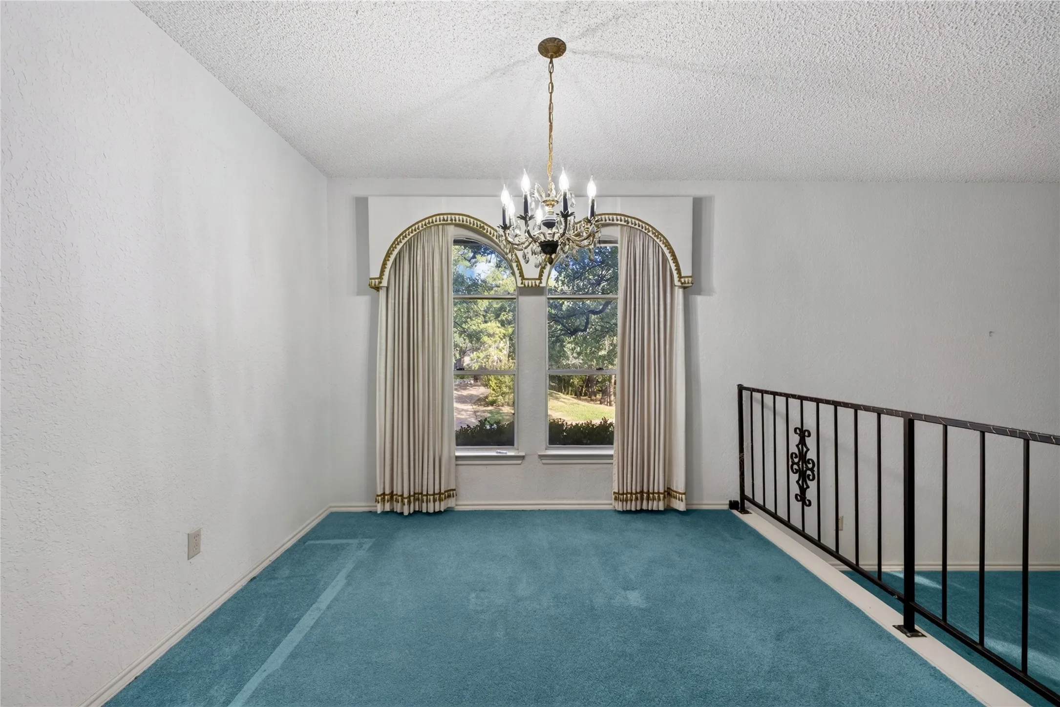 Dining room with arched window and wrought-iron railing overlooking the family room.