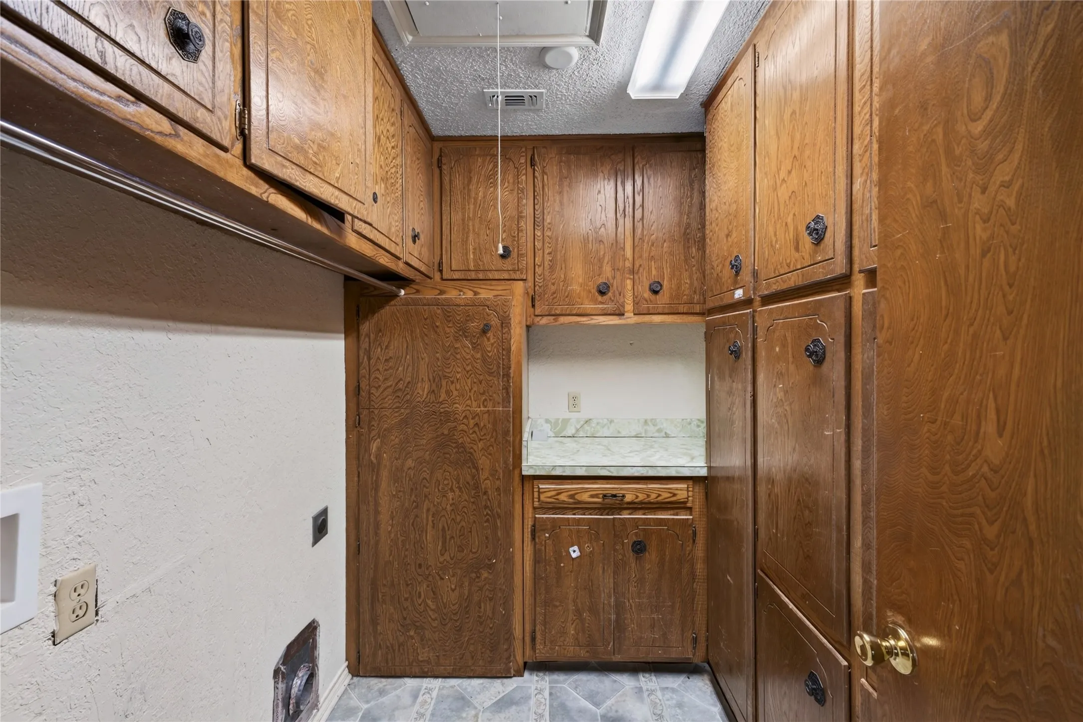 Extensive wood-finish cabinetry, integrated countertop, and tiled flooring