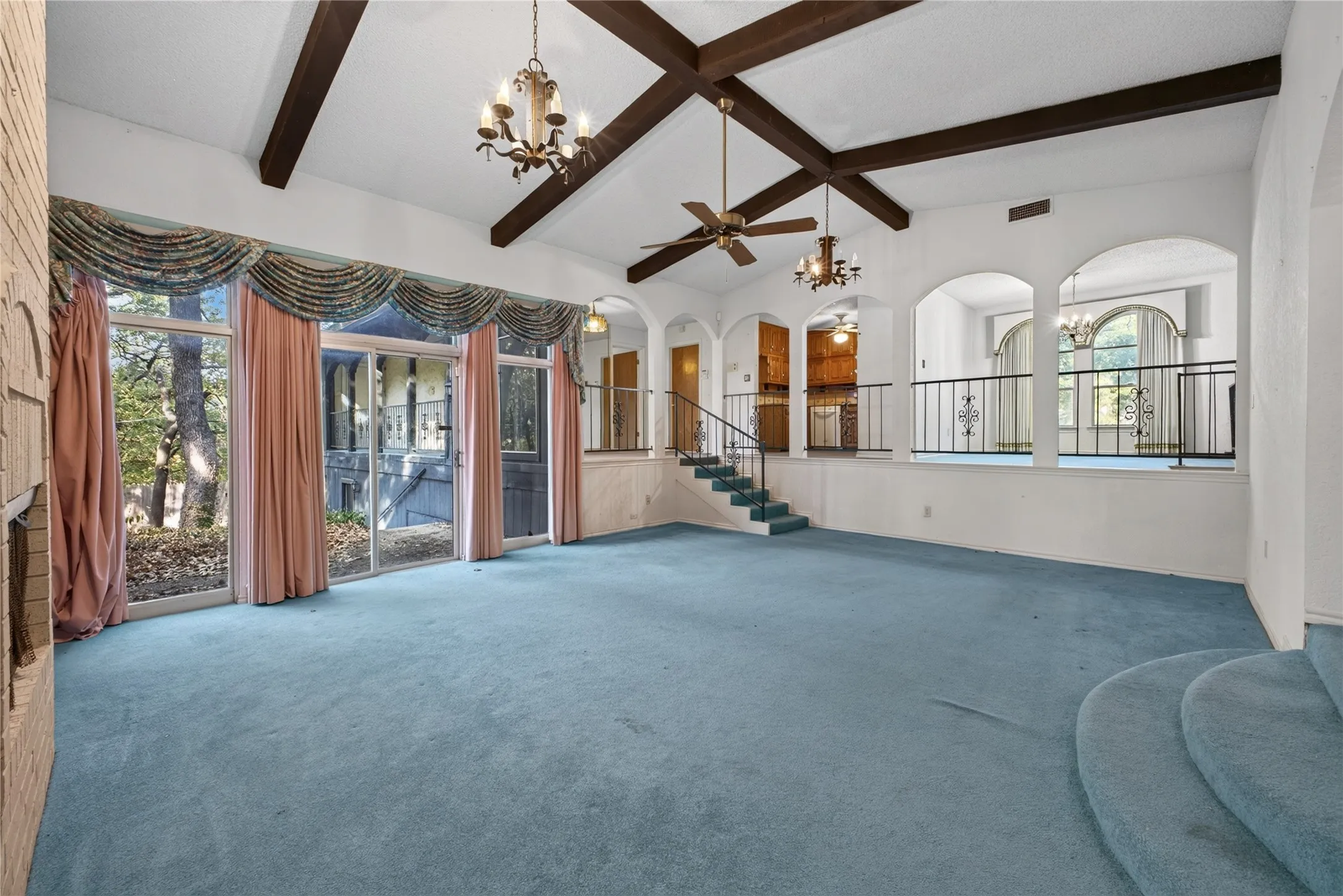 Vaulted family room with exposed beams and expansive glass overlooking the backyard.