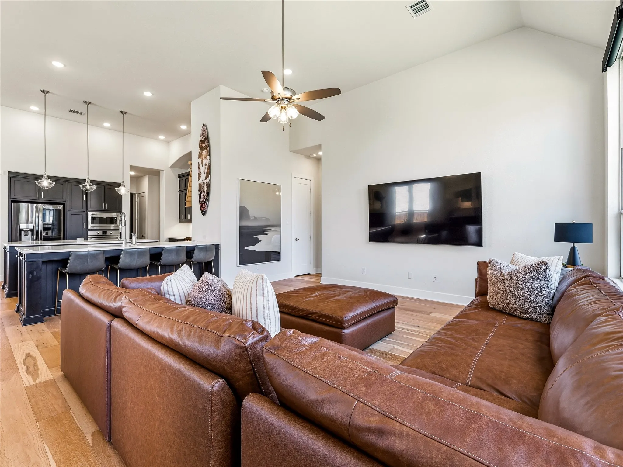 Open-concept living space with high vaulted ceilings, wood-finish flooring, and a ceiling fan