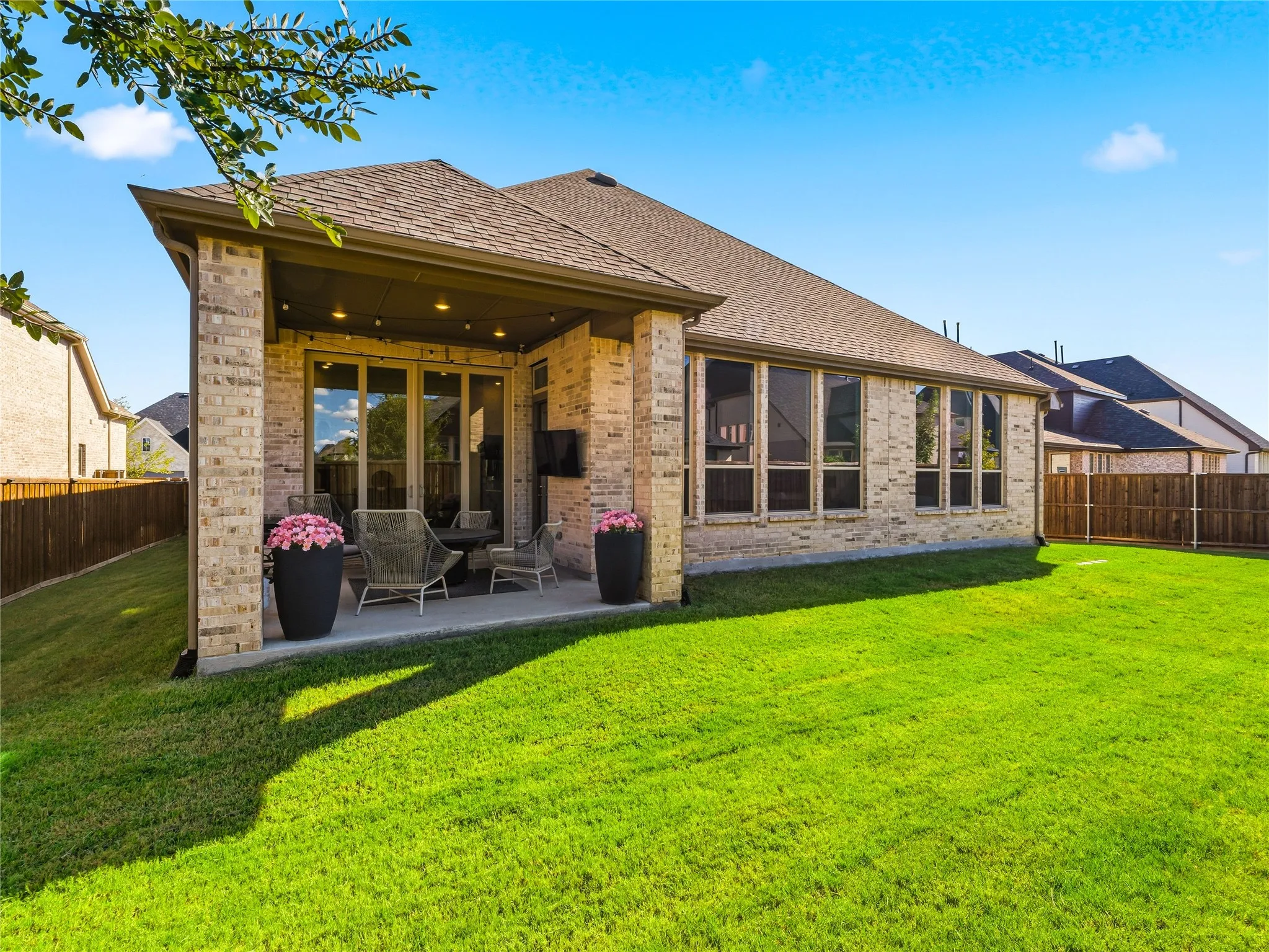 Expansive green lawn with a covered patio featuring recessed lighting and sliding glass doors