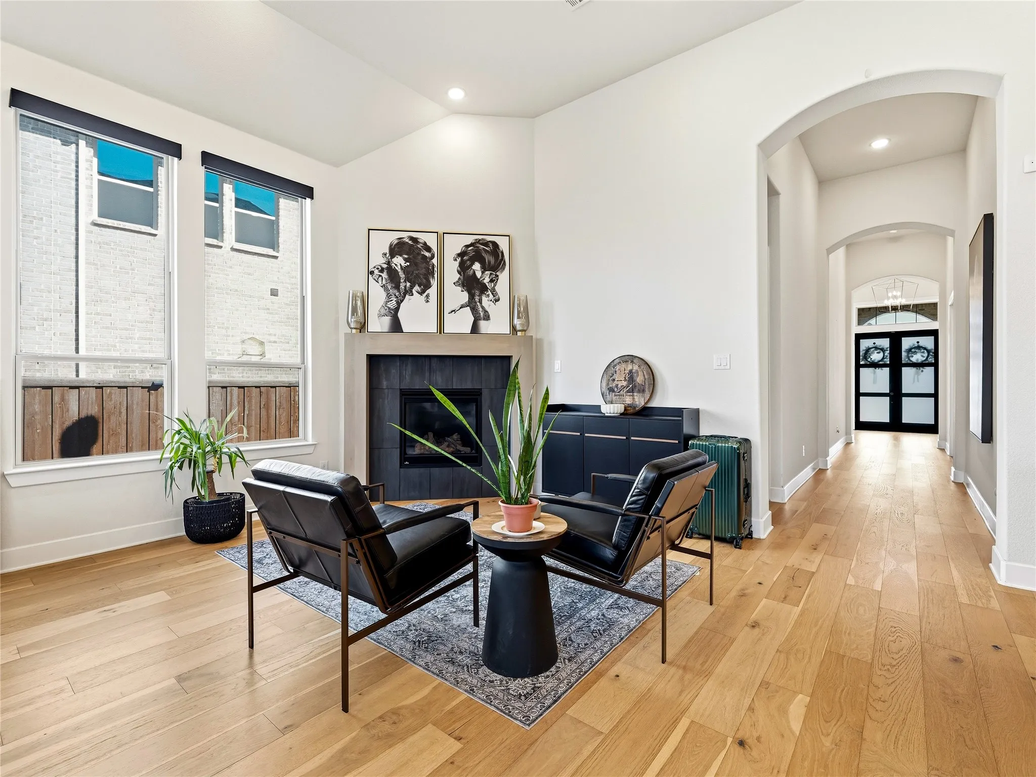 Vaulted ceilings, wood-finish flooring, a fireplace with a stone surround, and an arched hallway