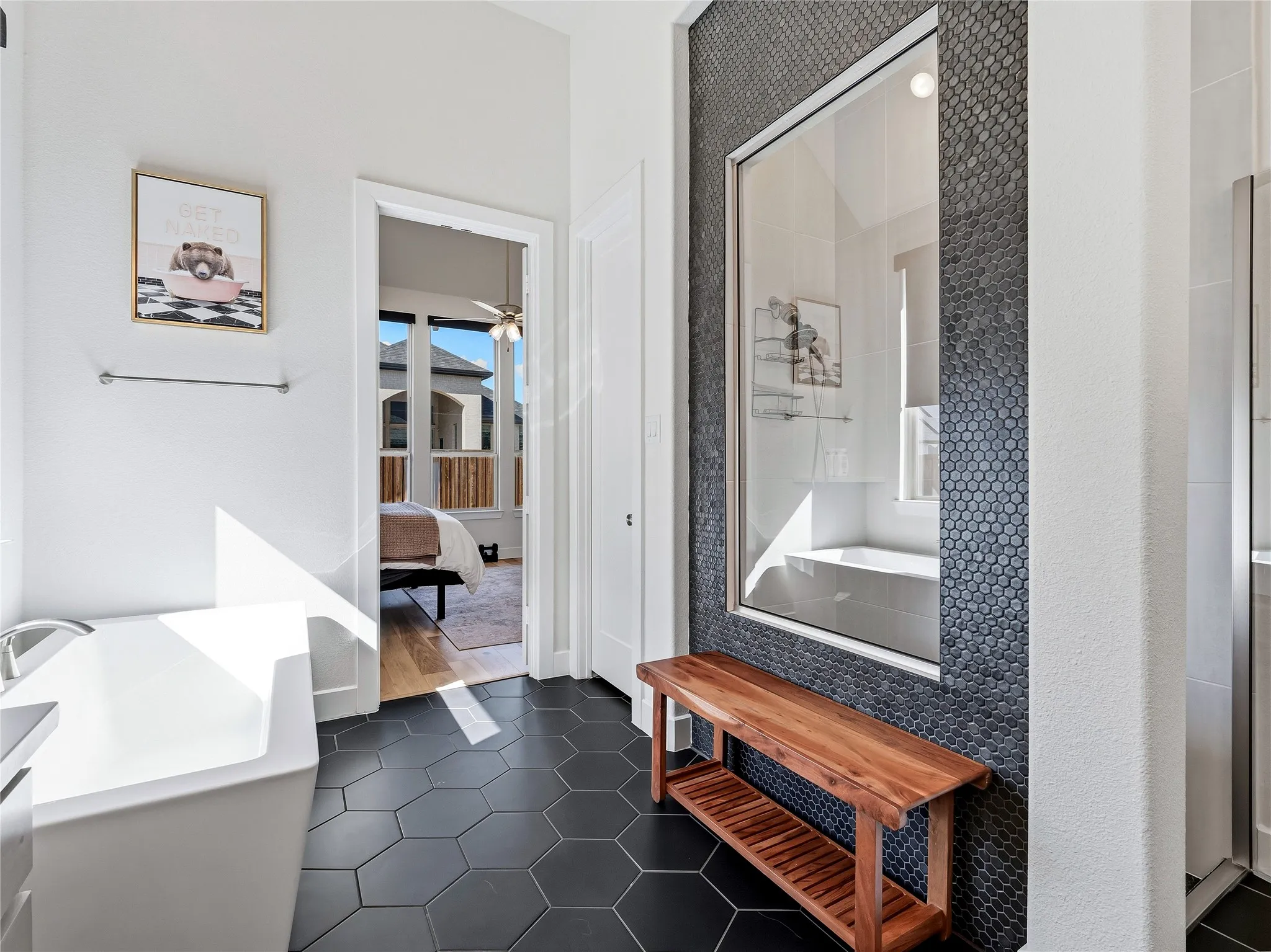 Freestanding soaking tub, hexagon tile flooring, walk-in shower with glass enclosure, penny tile shower wall, and built-in wooden bench