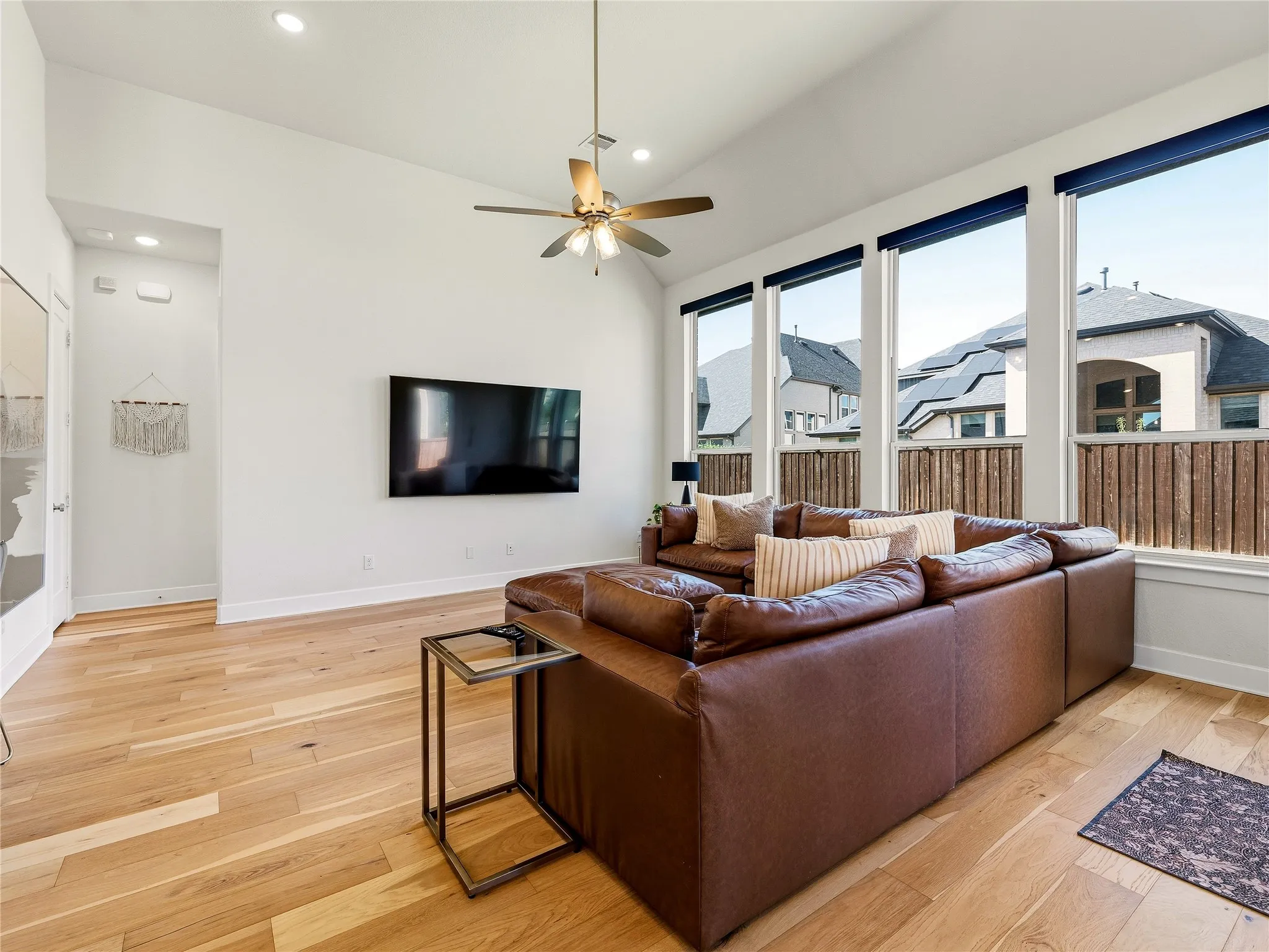Vaulted ceiling with a ceiling fan, recessed lighting, wood-finish flooring, and multiple tall windows