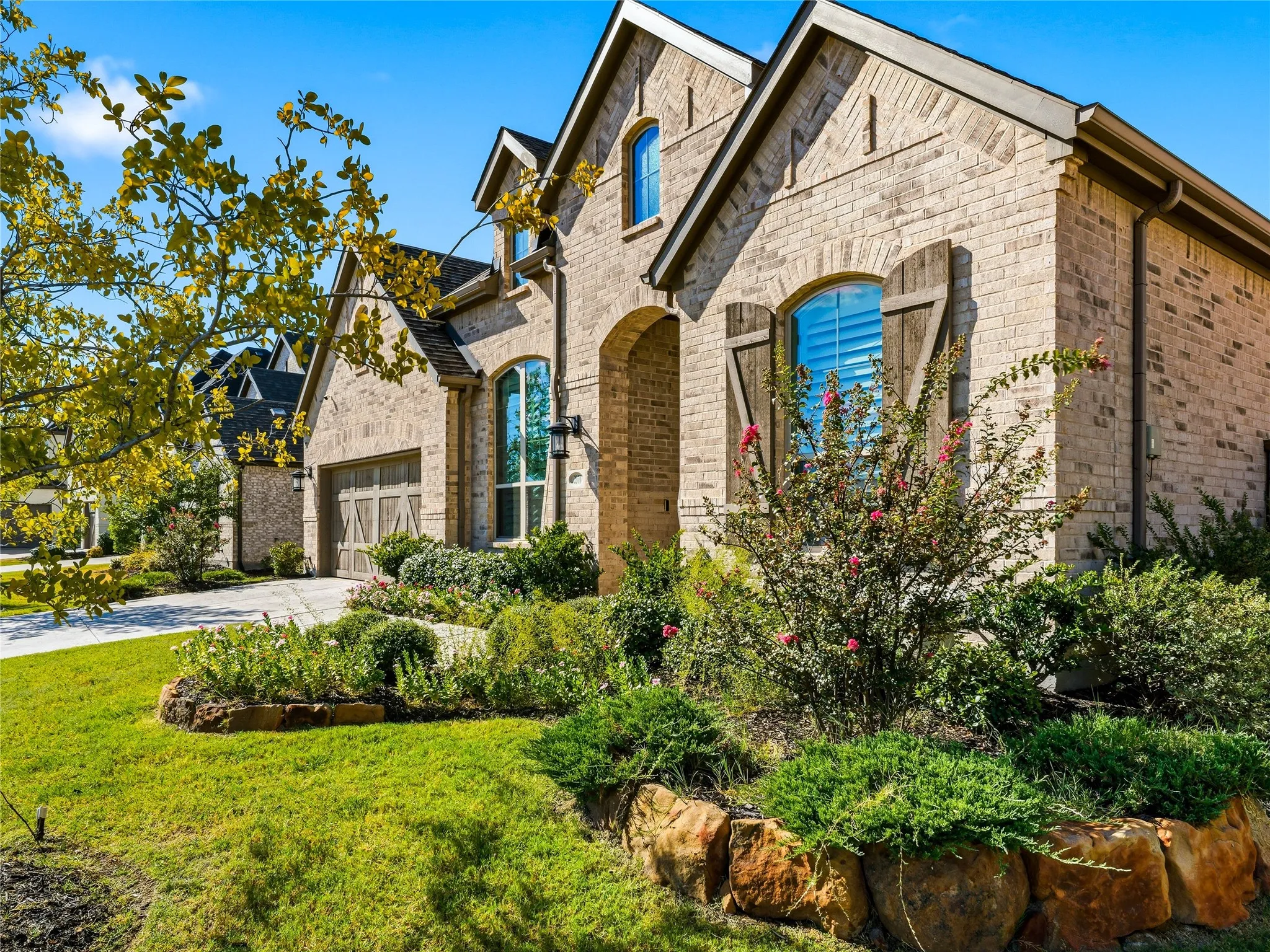 Brick exterior with arched windows, decorative shutters, and an attached garage