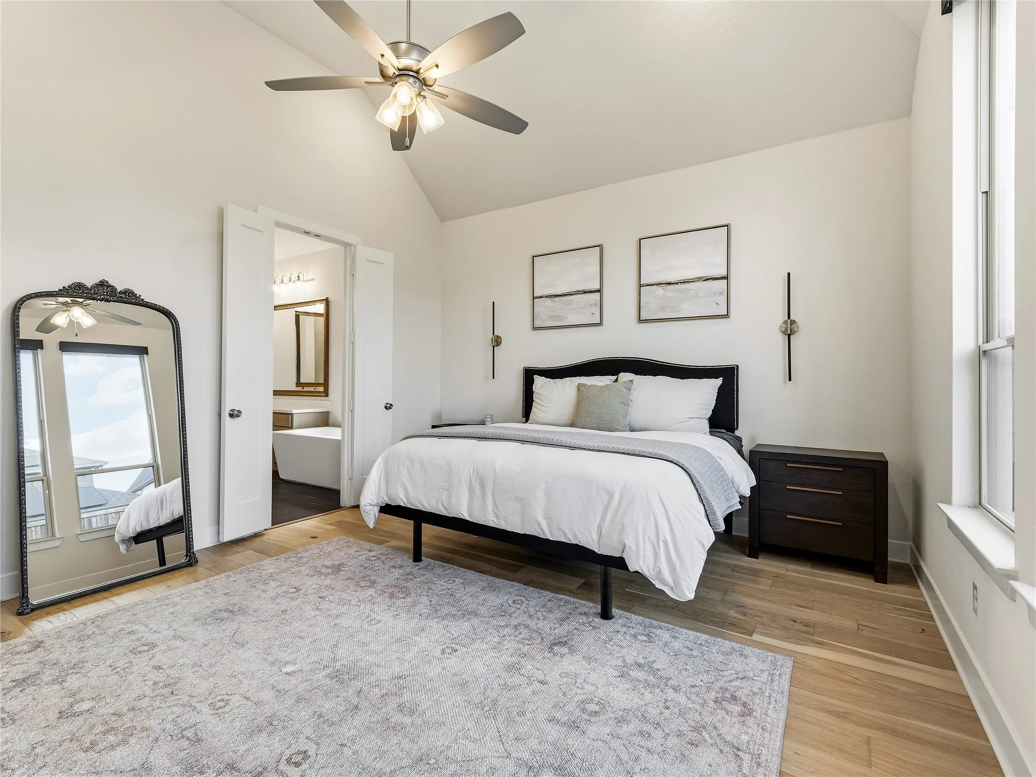 Vaulted ceiling with a ceiling fan, light wood-finish flooring, and natural light from a vertical window