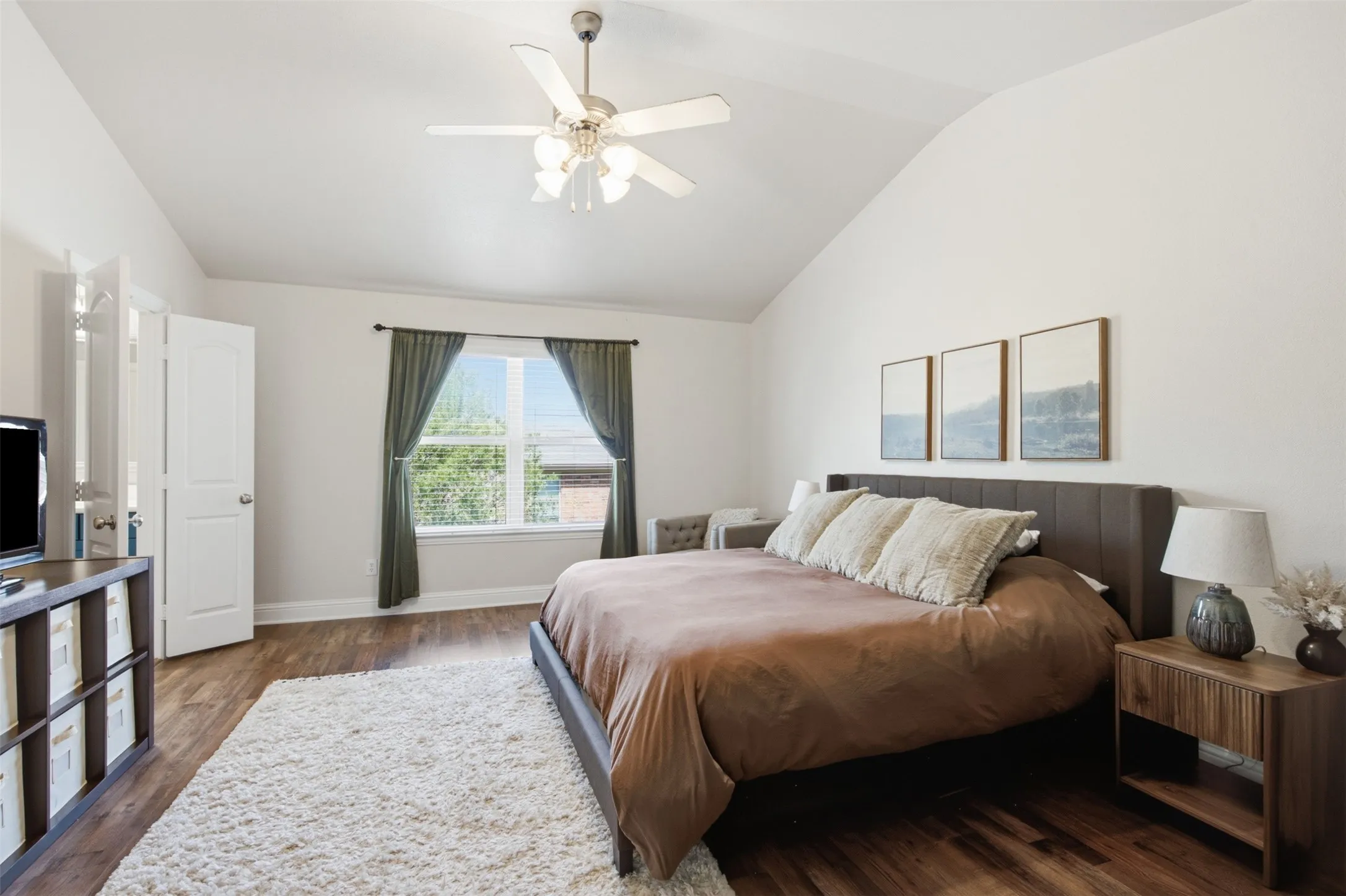 Vaulted ceiling with a ceiling fan, wood-finish flooring, a window with blinds, and white walls