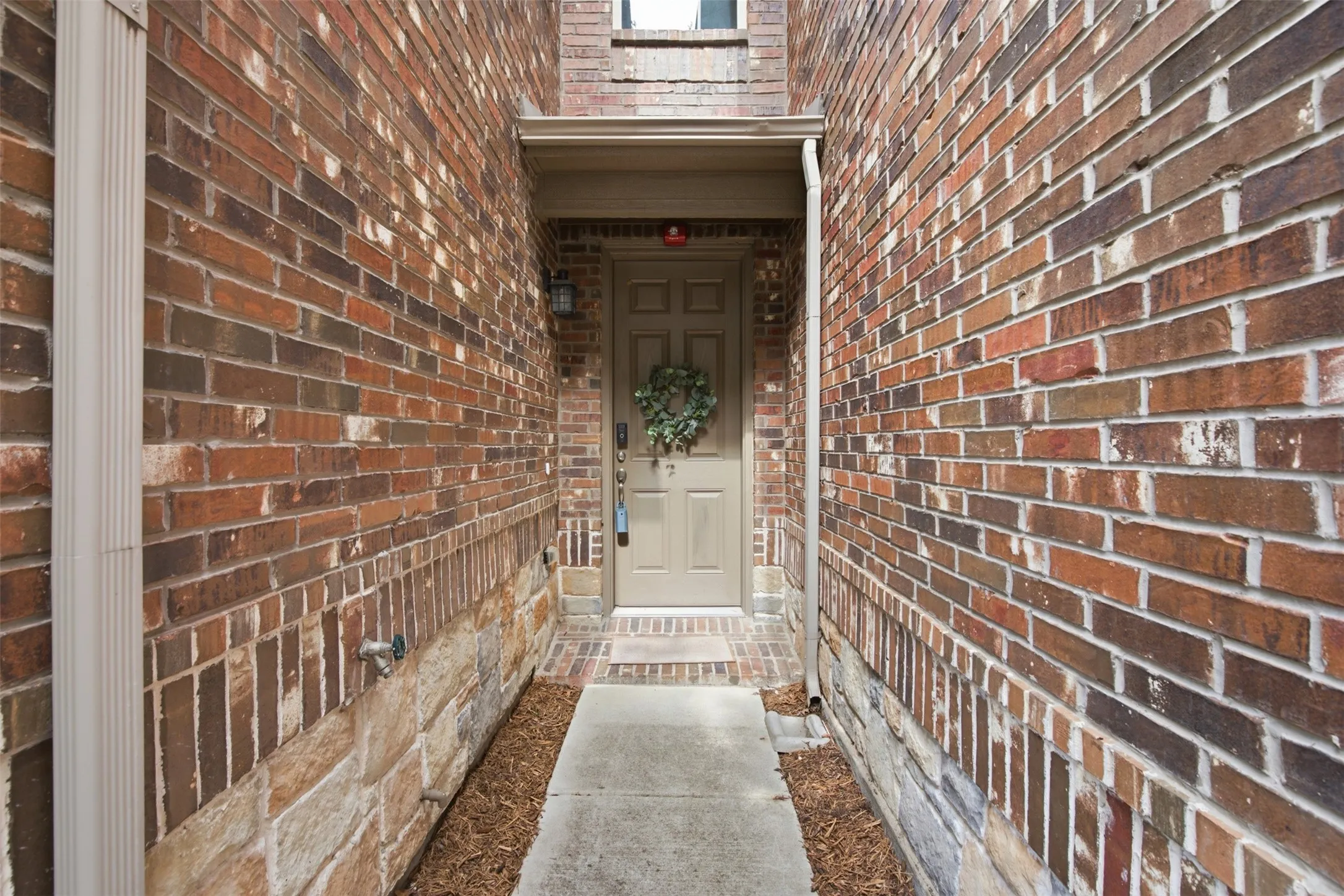 Brick exterior with stone foundation detailing, featuring a panel-style entry door and exterior wall sconces