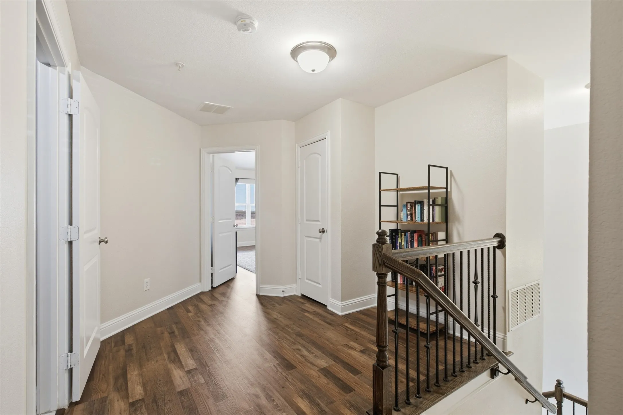 Wood-finish flooring, white paneled doors, and a wood and wrought iron staircase