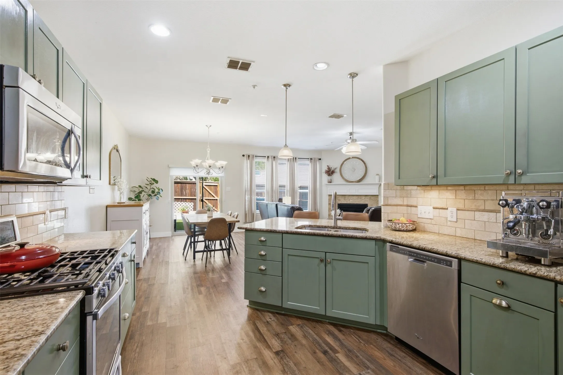 Kitchen featuring granite countertops, a subway tile backsplash, stainless steel appliances, and sage green cabinetry