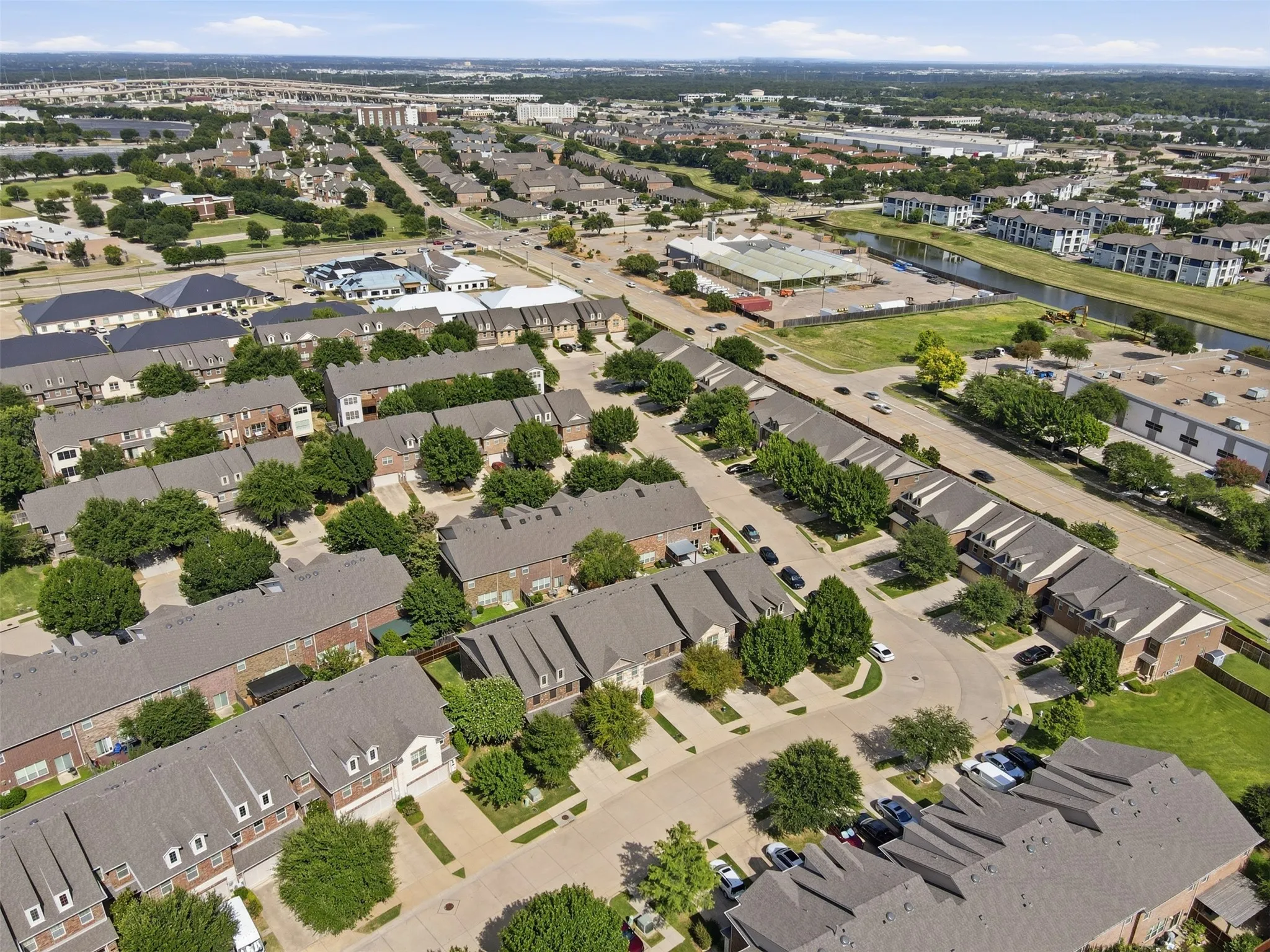 Neighborhood setting featuring multi-story residences with gabled roofs, a curved street, and mature trees