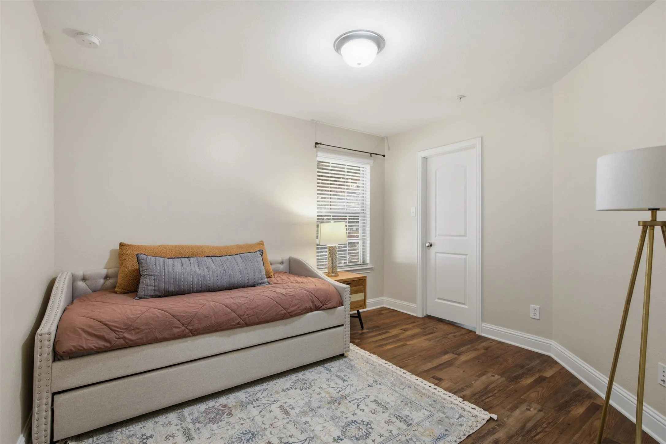 Wood-finish flooring, white trim, recessed lighting, and a white interior door