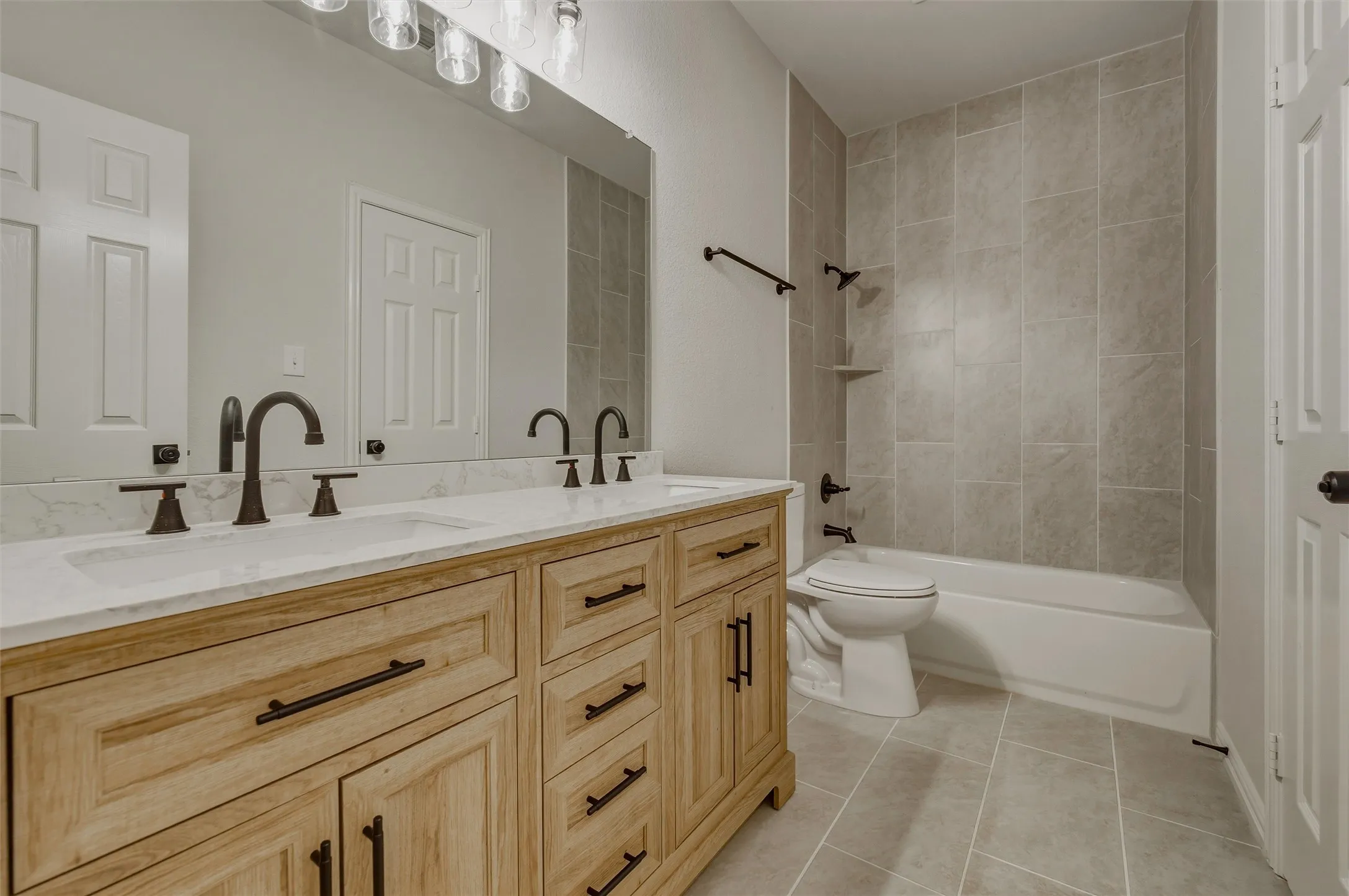 Dual vanity with wood-finish cabinetry and white countertops, featuring matte black fixtures