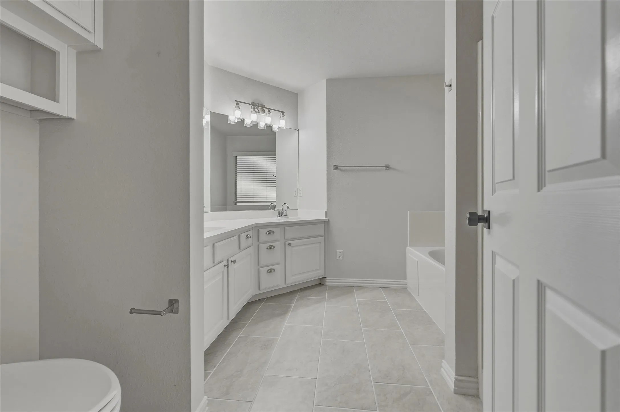 Dual vanity with white cabinetry, wall-mounted mirror, and overhead light fixture