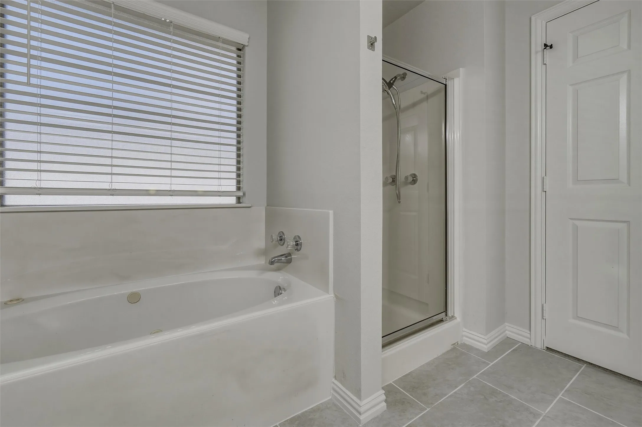 Recessed bathtub with chrome fixtures and an adjacent glass-enclosed shower