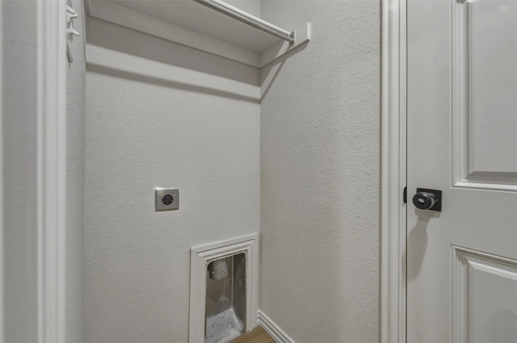 Dedicated utility area featuring a built-in shelf and hanging rod, electrical outlet, and plumbing hookups