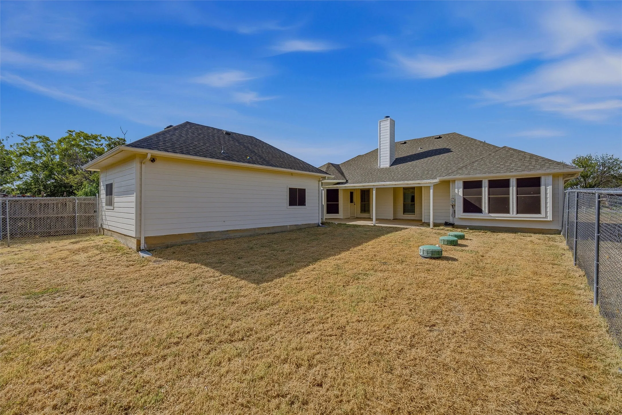 Expansive rear exterior featuring a covered patio, multiple windows, and a separate structure