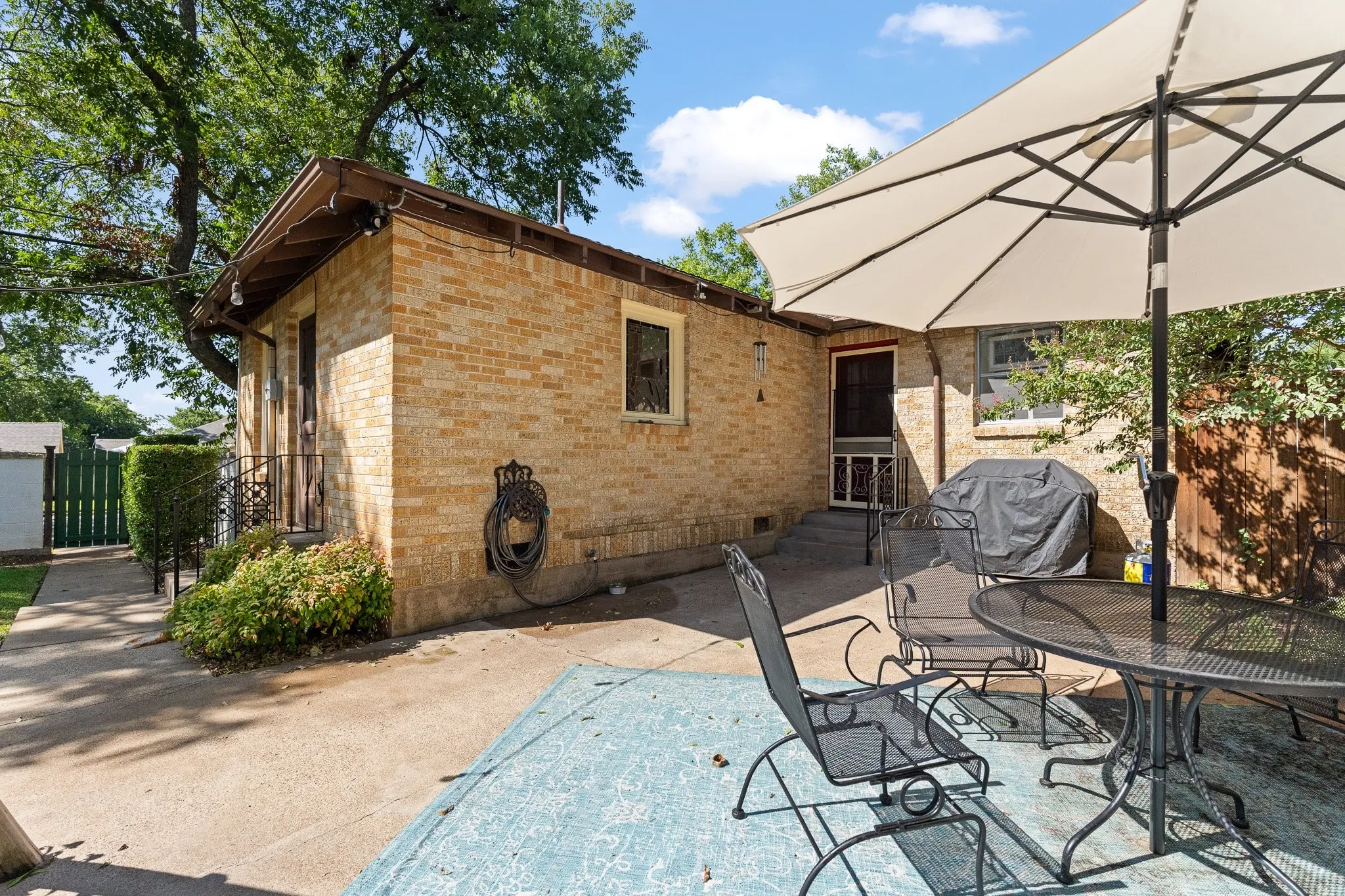 Here's a picture of the back patio and the door that leads to the kitchen. Notice the cute green gate to the side street on the left.