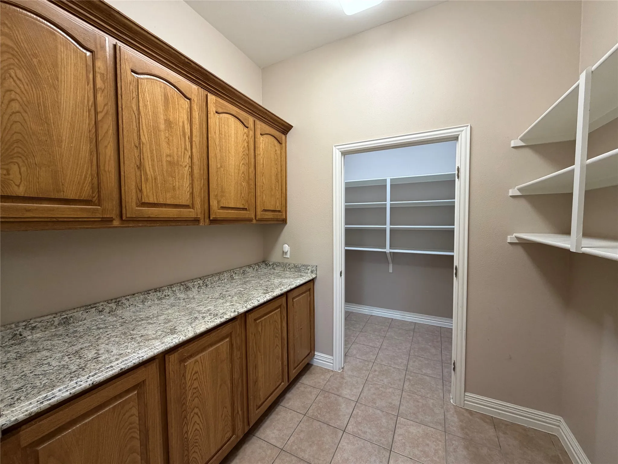 Copier room with built-in cabinets and counter, which leads in to extra storage room with built-in shelves.