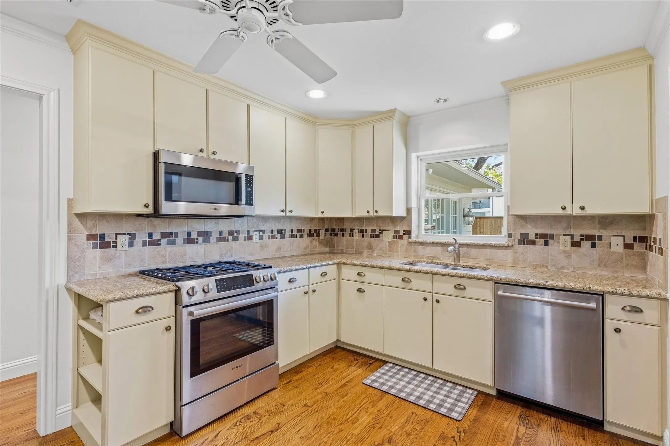 Kitchen featuring wood-finish flooring, recessed lighting, ceiling fan, stainless steel appliances, and ample cabinetry with crown molding