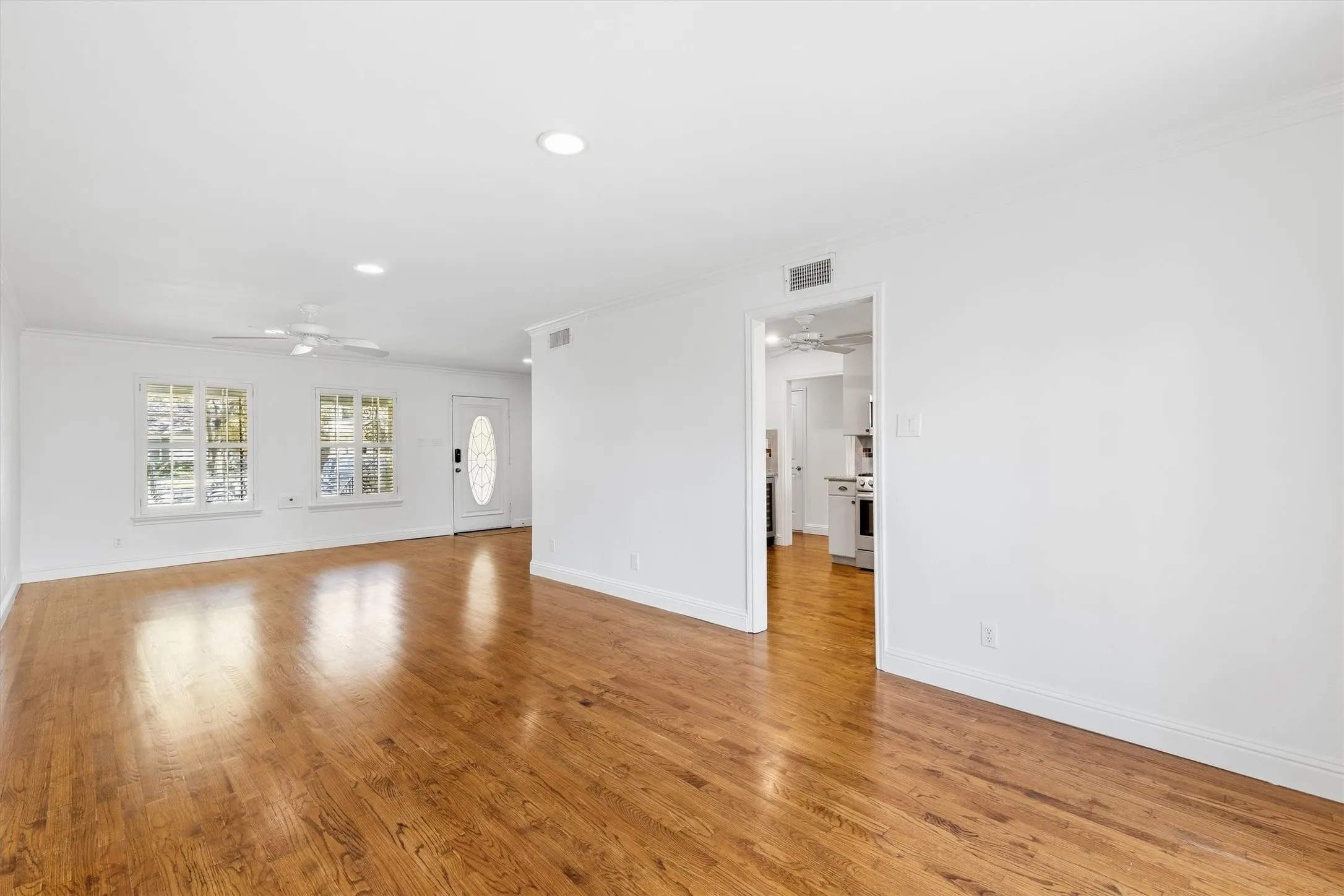 Hardwood flooring, recessed lighting, white walls, multiple windows, and a ceiling fan